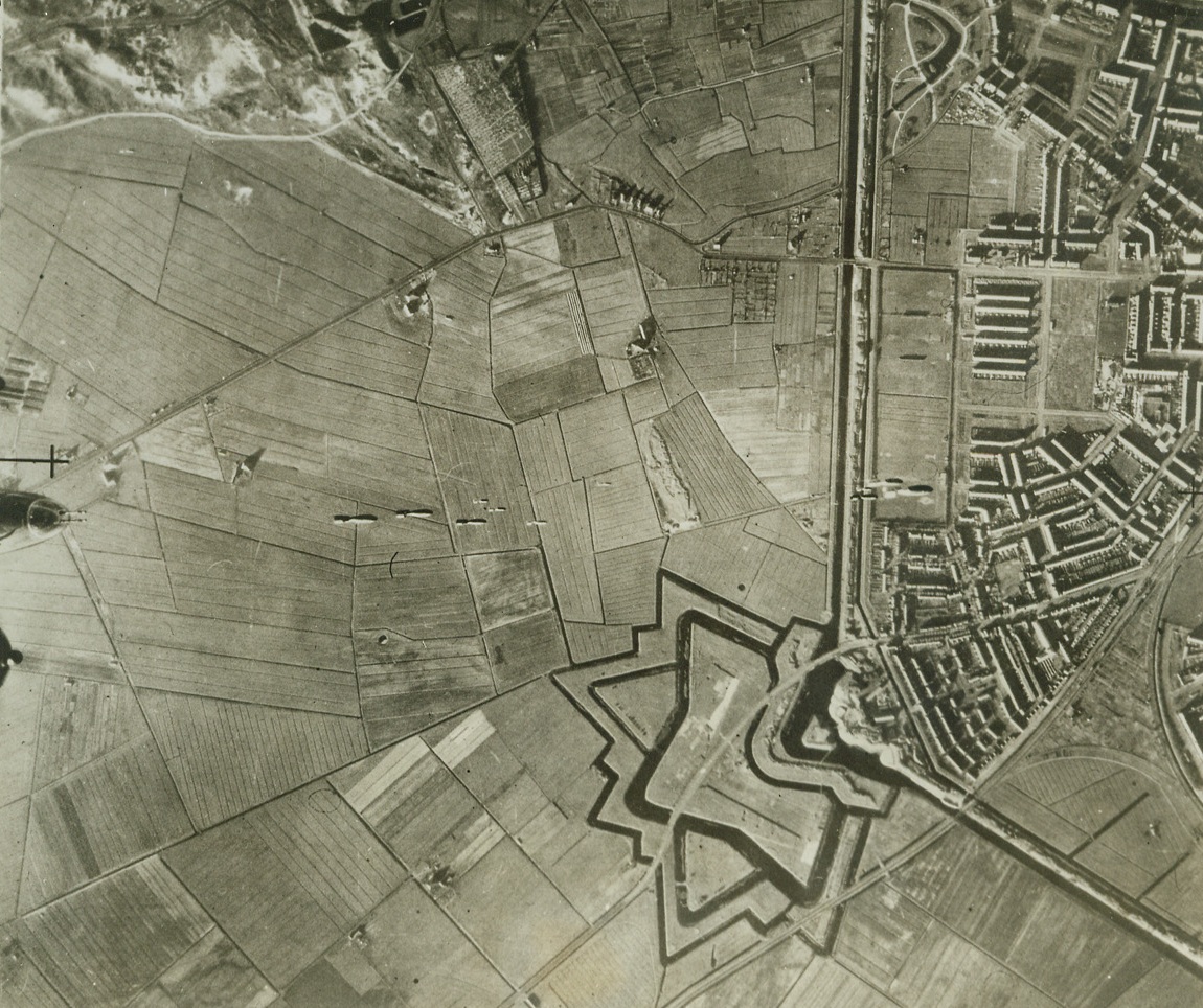 WARFARE—OLD AND NEW, 2/8/1943. HOLLAND—This aerial photo show R.A.F. bombs falling towards the docks at Den Helder in Holland. The nose of one of the attacking planes can be seen at the very bottom of the picture. The star-like pattern at the right is part of the ancient outer fortifications of Den Helder, which were the type used from the 16th century until Napoleon’s time. Credit: Acme;