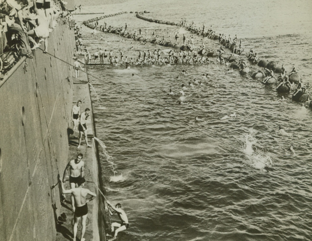 First Day “Ashore”, 2/12/1943. South Pacific – The minute their transport ship anchored, after a long and tedious convoy trip to a South Pacific island, all U.S. fighters aboard “abandoned ship” for a swim in the warm water.  Here, they take high dives, clamber aboard buoys, and thrash around in the water.  War, for the moment, is forgotten.Credit Line (ACME);