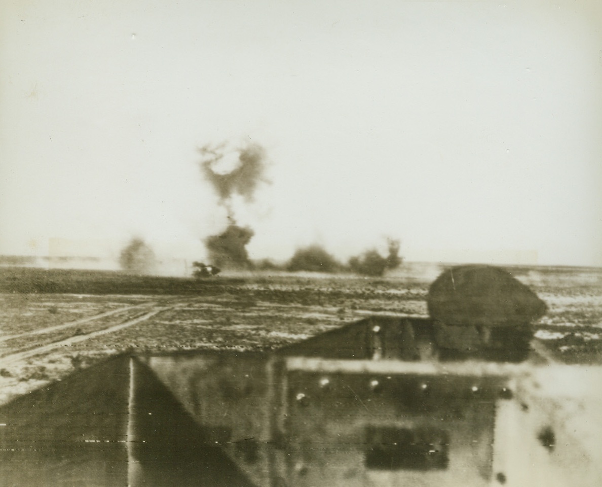 Blasting the Mareth Line, 3/25/1943. Tunisia – This is the first pictures showing action along the Mareth line, where the British Eighth Army is blasting at Rommel’s toughest defense.  This view from an armored scout car shows a “Bangalore” torpedo being exploded to force a gap in the barbed wire around a minefield.  The torpedo is an 8 to 10 – inch pipe filled with dynamite which is placed under the wire to make a breach so that soldiers van get through. It was named after a town in India, where it was first used. Credit line (ACME radio photo);