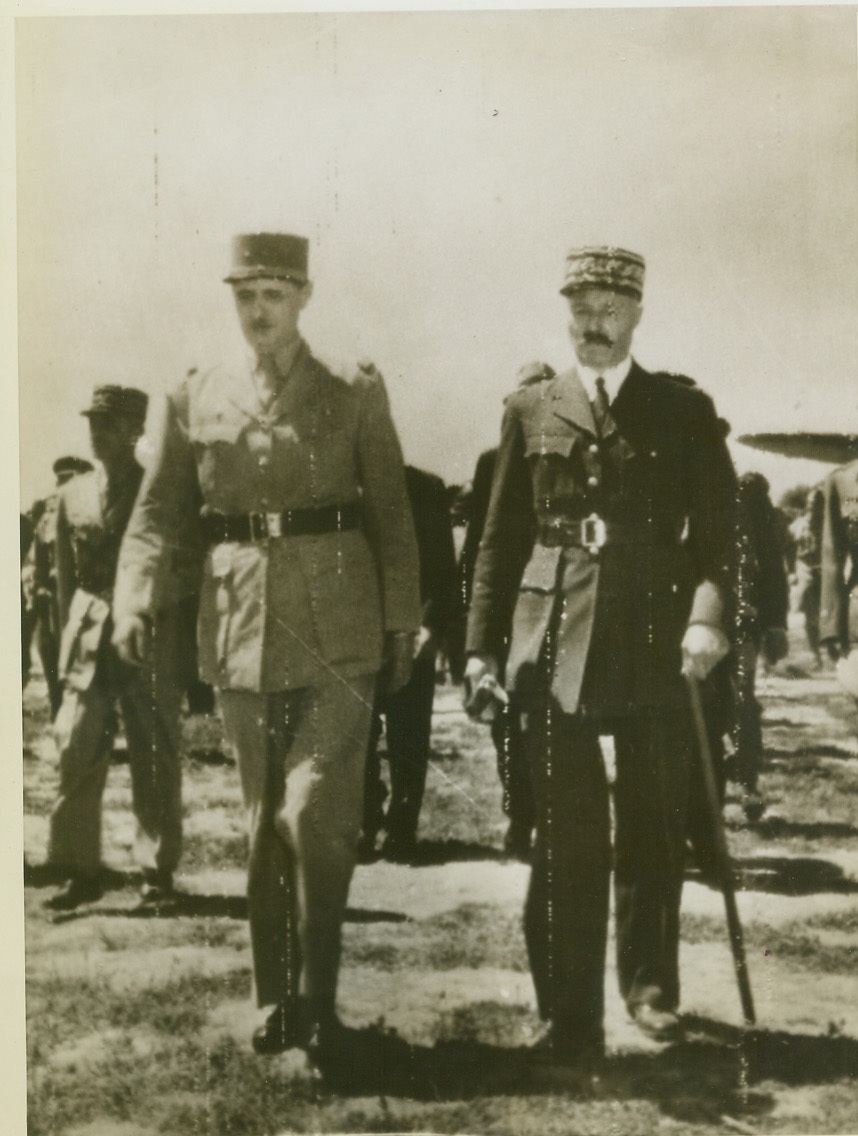 HERALDING FRENCH UNITY, 5/31/1943. ALGIERS – After an exchange of salutes and handshakes, General Charles De Gaulle (left) and General Henri Giraud leave the airport outside of Algiers where the Fighting French General landed May 30 for the long expected meeting. A very select committee greeted De Gaulle –Vichyites excluded. Although no public announcement of De Gaulle’s arrival was posted, the North African grapevine drew cheering crowds into the streets with cries of “Vive De Gaulle.” Credit: OWI Radiophoto from ACME;