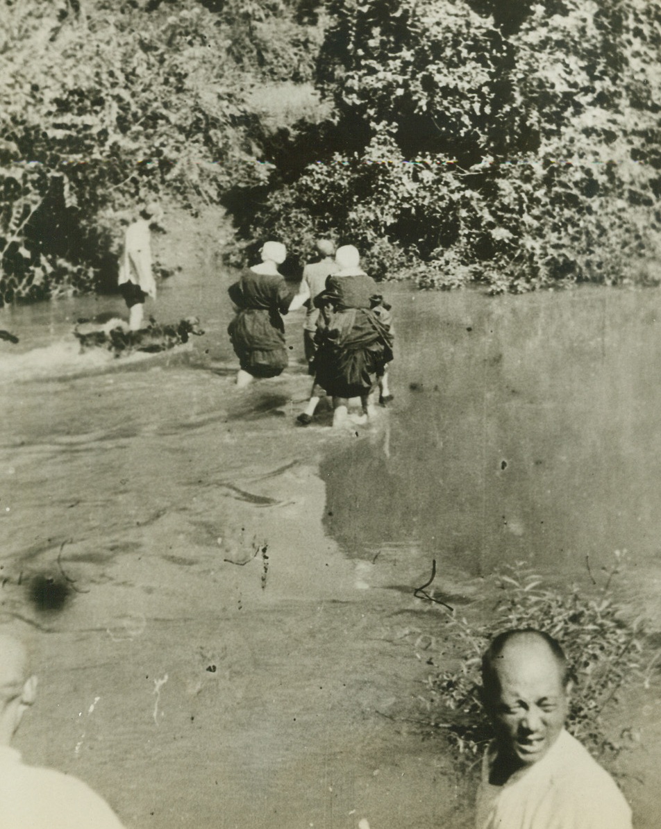 JAP SAVAGERY IN KIANGSI PROVINCE, 5/21/1943. From the camera of Vincentian priests, who served as missionaries in the Chinese Province of Kiangsi in October, 1942, when savage Jap troops visited the countryside to bring death and destruction to tiny towns that gave aid to General Jimmy Doolittle and his men, comes an eloquent record of the sufferings of the Chinese at the hands of brutal, vengeance-seeking Japan. Brought out of China by three priests and five American Sisters of Charity, who hid in the hills while the towns were laid waste, the pictures show violence that far surpasses damage done in modern bombing raids. The Chinese were tortured savagely and put to death en masse. Although the Japs had two objectives-the air field and 200 miles of railroad from Ying-tan to Chin-nua in Chekiang the general conduct of the rail was a punitive one, for it was here that American fliers were fed and treated after their raid of April 18, 1942. Fleeing China after the raid, the eight missionaries traveled on foot, by bus, and finally by boat and plane, reaching the Western Hemisphere five months later. The pictures were obtained in St. Louis from Father Paul Lloyd, director of the Vincentian Foreign Mission Society, and Father George Yager, the Vincentian priest who witnessed the raid and supplied captions for the following photos.  Holding their skirts high, American Sisters of Charity splash through a mountain stream as they flee the fast-approaching Jap Army of destruction. The Sisters abandoned their traditional headdress for the flight, to prevent the large, white headpieces from attracting the attention of aircraft.  Credit: ACME.;