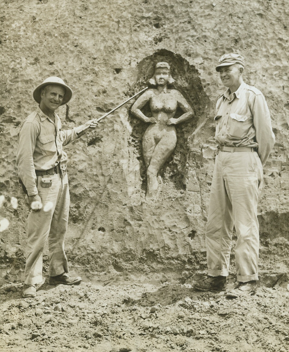 Lady In A Claybank, 6/11/1943. Somewhere in New Guinea – Tho’ building a highway across New Guinea and forced to cope with some of the world’s most difficult terrain as they found their road over jungles, mountains and swamps, American Army engineers never lost their sense of humor.  Taking time out from his work, one of the Yanks carved this bit of “inspiration” for the workers out of a soft claybank.  Inspecting the work of art are Colonel H.G. Lauterbach, Commander of a U.S. engineer’s unit; and Brig. Gen. Jens A. Doe (right), who commands an American unit “somewhere in New Guinea”. Credit line –WP- (ACME);