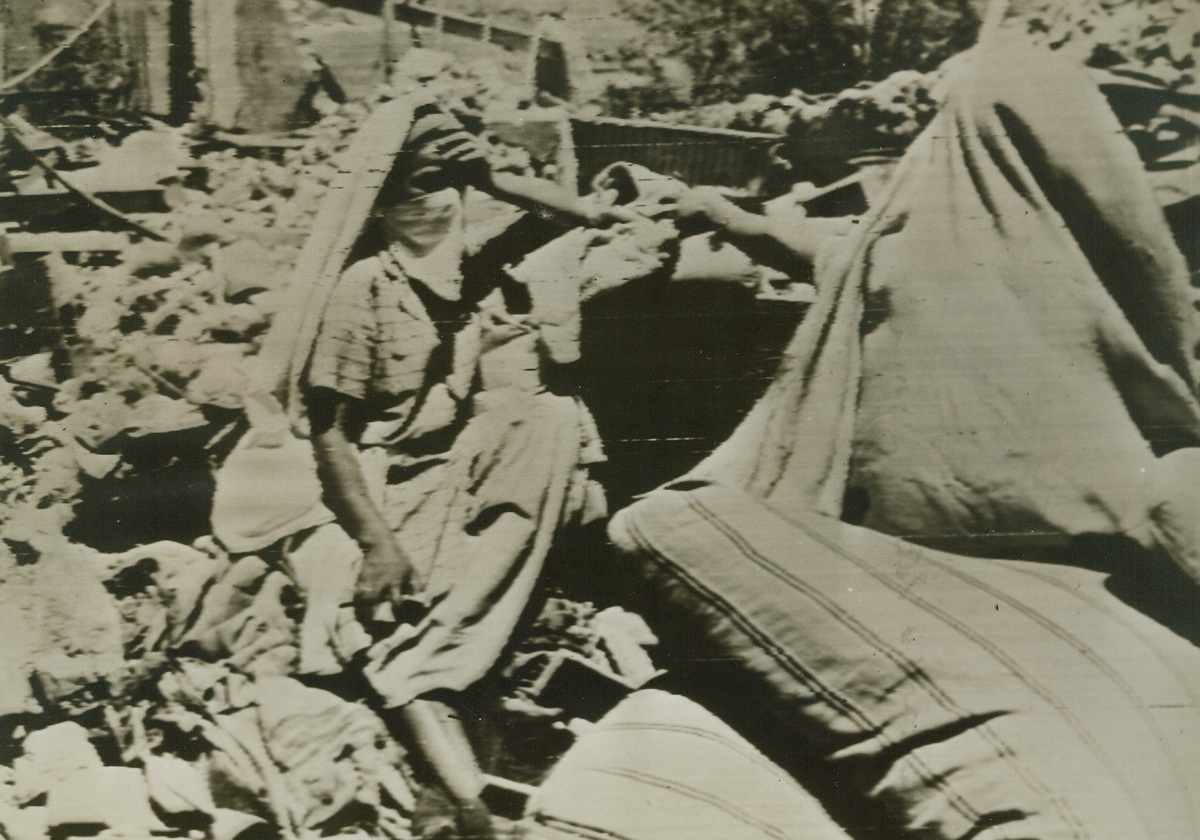 Left Homeless By Axis Bombs, 6/7/1943. Algiers – In deep sorrow, this Algerian woman sits amidst the ruins of her home, after axis raiders had blasted the residential section of the city recently.Credit line (ACME photo via U.S. Signal Corps);