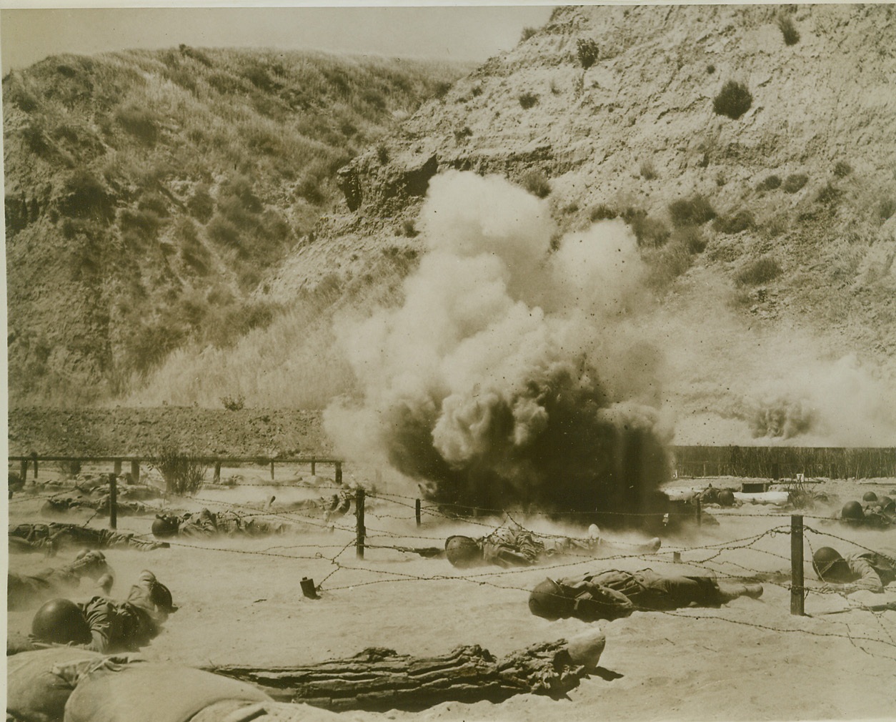 This is War – Almost, 6/24/1943. CAMP ROBERTS, CALIF. – Actual battle will hold few surprises and no fears for trainees schooled at Camp Roberts, for they “fight” under realistic battle conditions on the Camp’s new infiltration course. These infantry trainees flatten themselves on the ground as live machine gun bullets cut the air a few inches above their heads and a land mine explodes right in their midst. Credit (U.S. Signal Corps Photo from ACME);