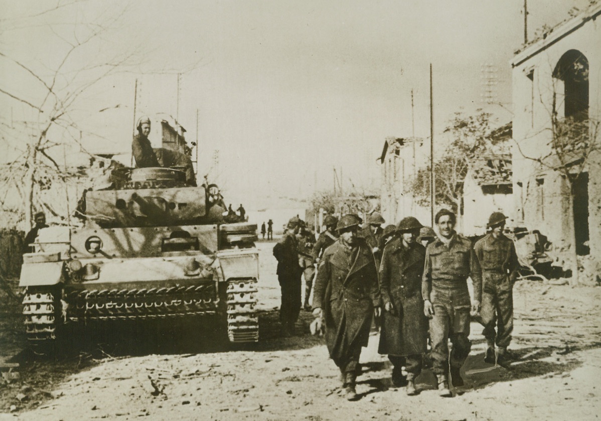“British Prisoners” – Nazis Say, 1/6/1943. This German photo, received in New York through a neutral country and via London, purports to show, according to the caption, “German tanks and tank-grenadiers mop up in Tebourba (Tunisia) after the fall of that town.  The tommies have left their hiding place and are taken prisoners.” Credit line (ACME);