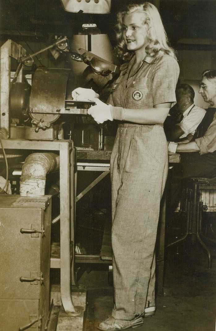 Ingrid in Overalls, 9/23/1943. Minneapolis, Minn. – Here’s the face that decorated countless barracks walls – but pretty Ingrid Vallo has hidden her eye-catching gams in a pair of war worker’s overalls, for the duration. Even the lovely blonde tresses are hidden beneath a safety cap as she works at her drill press in a Minneapolis war plant. See ACME photo #646764 for a glimpse of Ingrid in peacetime as an eye-filling pin-up. Credit: (ACME);