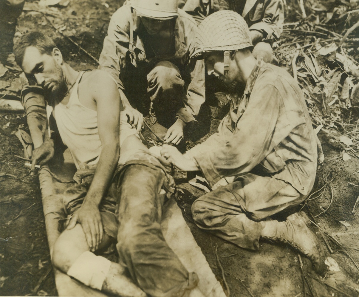 Jungle First Aid, 9/21/1943. New Georgia Island – Wounded by a grenade, Pvt. Anthony Sorice (left), is taped up by his brother-in-law, Joseph Alderuccio, (right).  Both men are from New Britain, Conn., and are members of the same infantry unit on New Georgia Island.  Alderuccio and five others carried Sorice a mile through the jungle before reaching a jeep trail, where they put in on a jeep for evacuation to the rear, after the Japs were driven out in bloody fighting at Munda Point, only isolated pockets of resistance remain. Credit line (U.S. Signal Corps photo from ACME);