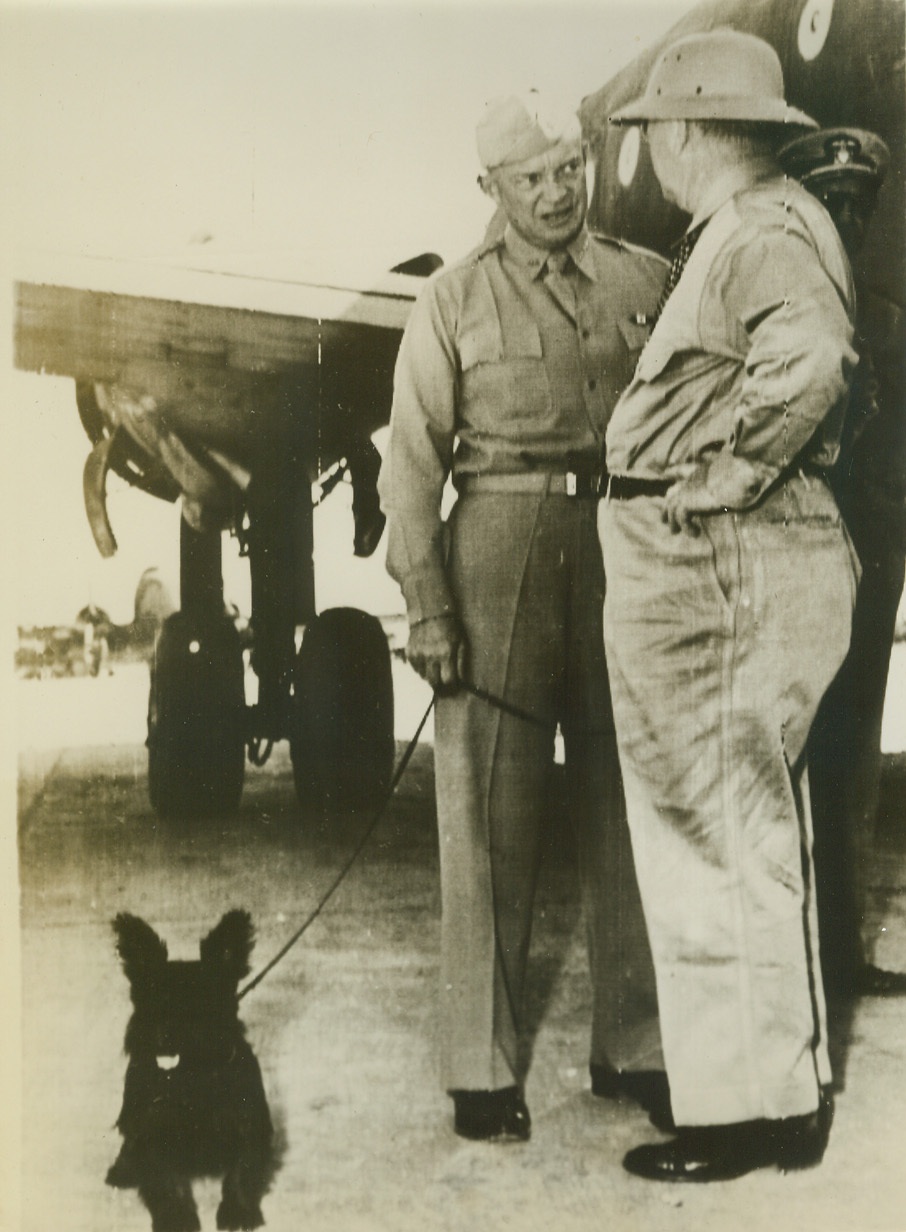 SECRETARY KNOX TOURS ITALIAN FRONT, 10/4/1943.  This photo, flashed to the U.S. today by radiotelephoto shows Col. Frank Knox, Secretary of the Navy, (right), as he conferred with Gen. Dwight D. Eisenhower, Allied Commander in the North African Theatre, after the Secretary’s arrival at an airport for a tour of the Italian Front. With them is Gen. Eisenhower’s dog Telex. Credit: U.S. Navy photo via OWI Radiophoto from ACME;