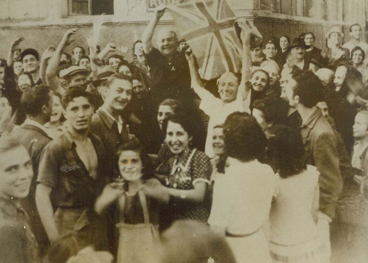 No More Swastikas, 10/11/1943. CORSICA—Two cheering and shouting elderly Corsicans wave the Union Jack which replaces the hated Nazi Swastika in their town of Ajaccio, the capital of the island now held by the Allies. The minute the town fell to Allied troops, the citizens turned out for riotous celebration.  Credit: ACME.;