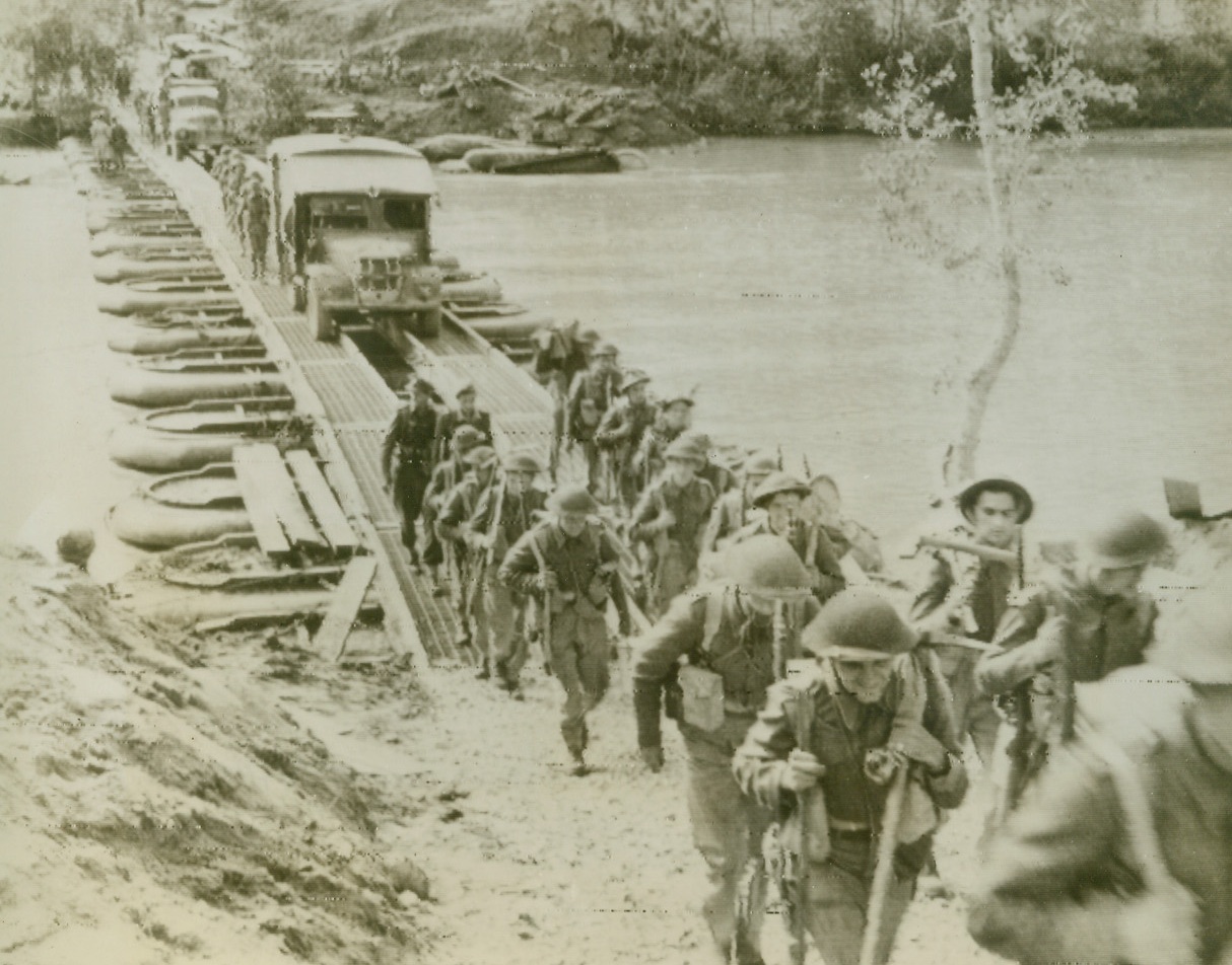 BRITISH PUSH AHEAD, 10/21/1943. ITALY—Pushing ahead in Italy, British Infantrymen tramp across a pontoon bridge, spanning the Volturno River, that was built by American engineers. Photo radioed to New York from Algiers today (October 21st). Credit: Acme radiophoto;
