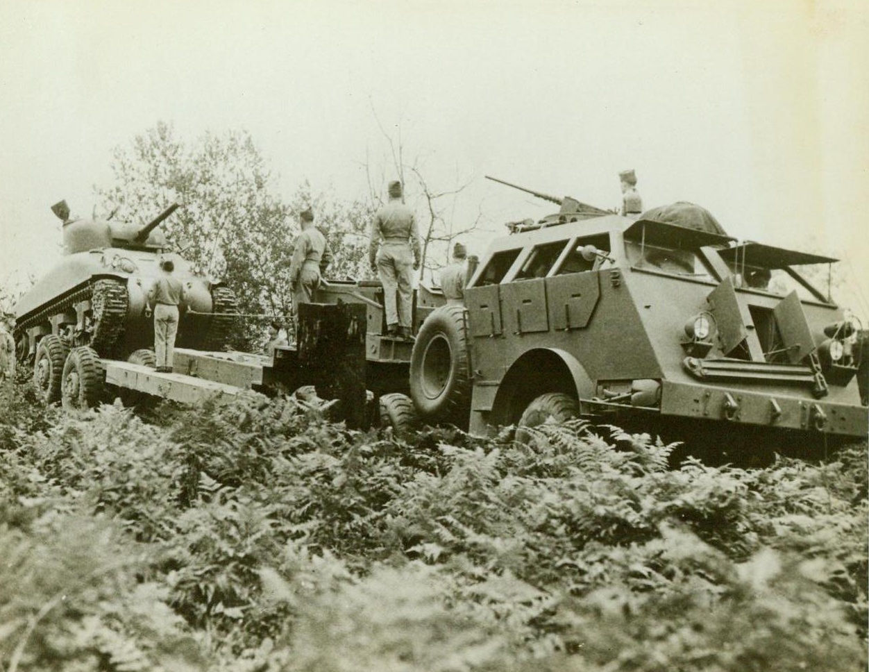 And Now, Tanks Ride To Battle, 10/28/1943. The tank recovery vehicle, known to the War Dep't as the M-25, takes on a tank. These gross vehicles, weighing over 40 tons carry tanks or armored vehicles to front lines and disabled ones from the battlefields for repairs. They make it possible for tanks to enter battle with full fuel tanks and cool motors. Each vehicle is armed to protect itself from enemy ground and air attack and can operate on its own for four days. 10/28/43 (ACME);