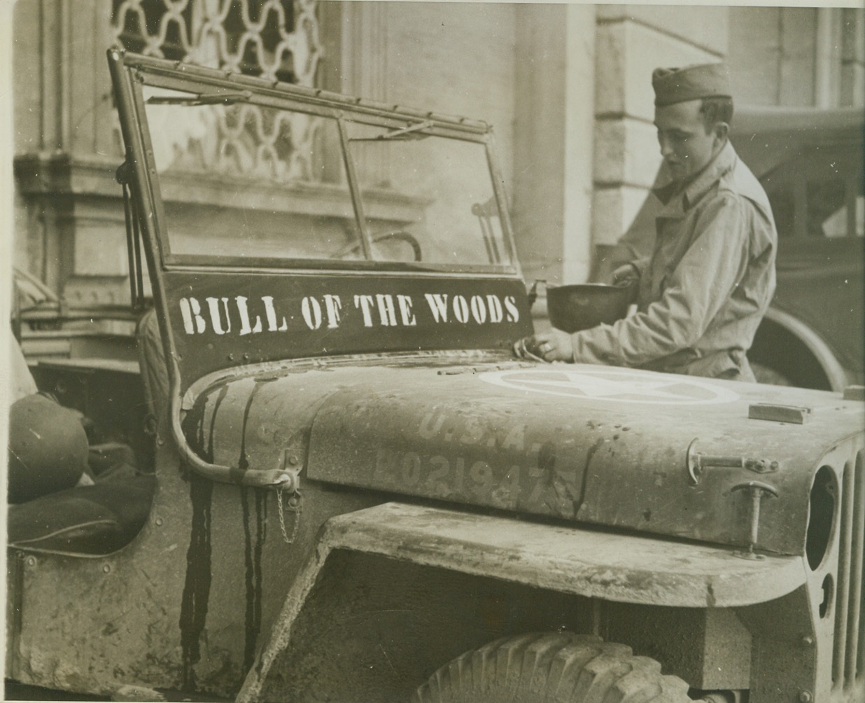 Named for His Favorite, 11/28/1943. Somewhere in Italy – “Bull of the Woods” is the favorite comic strip character of Private Robert Coba of Pittsburg, Kansas, so he gave that name to the Jeep he drives around the Italian front. Here, the soldier wipes mud from the little car that has seen service in Africa as well as Italy. Credit: (Photo by Bert Brandt, AMCE, photographer for War Picture Pool);