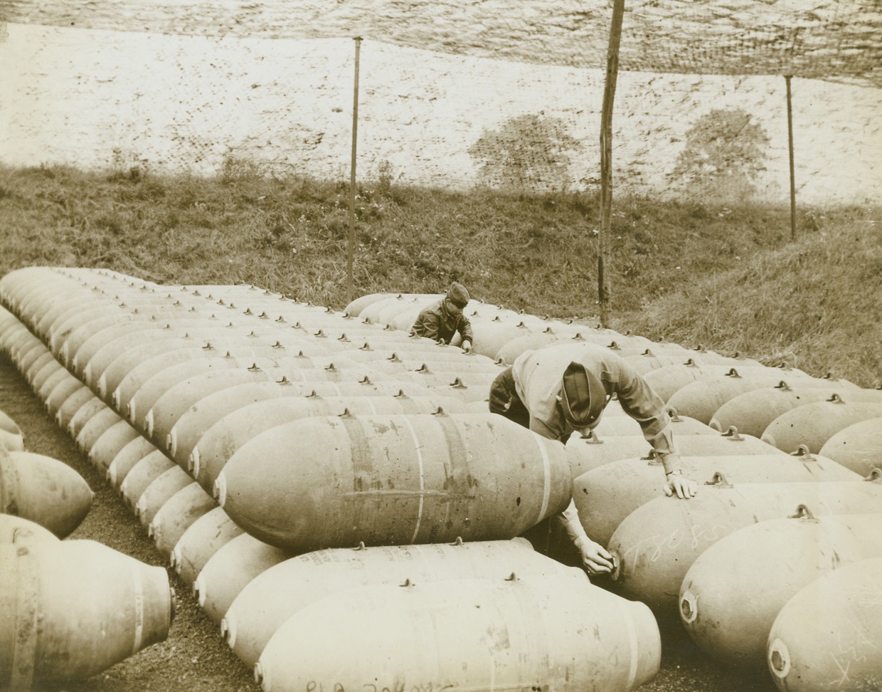 Ready for Delivery, 11/21/1943. Somewhere in England—These big babies, 1000 and 2000 pound bombs stacked in a supply dump somewhere in England, are destined for delivery over targets in France, Germany and Belgium. Combining their efforts to flatten Hitler’s Europe, bombers of the RAF and the US Army Air Forces have sent millions of tons of destruction down upon the continent. As many as 6000 tons have been dropped within a 48 hour period. Credit: ACME.;