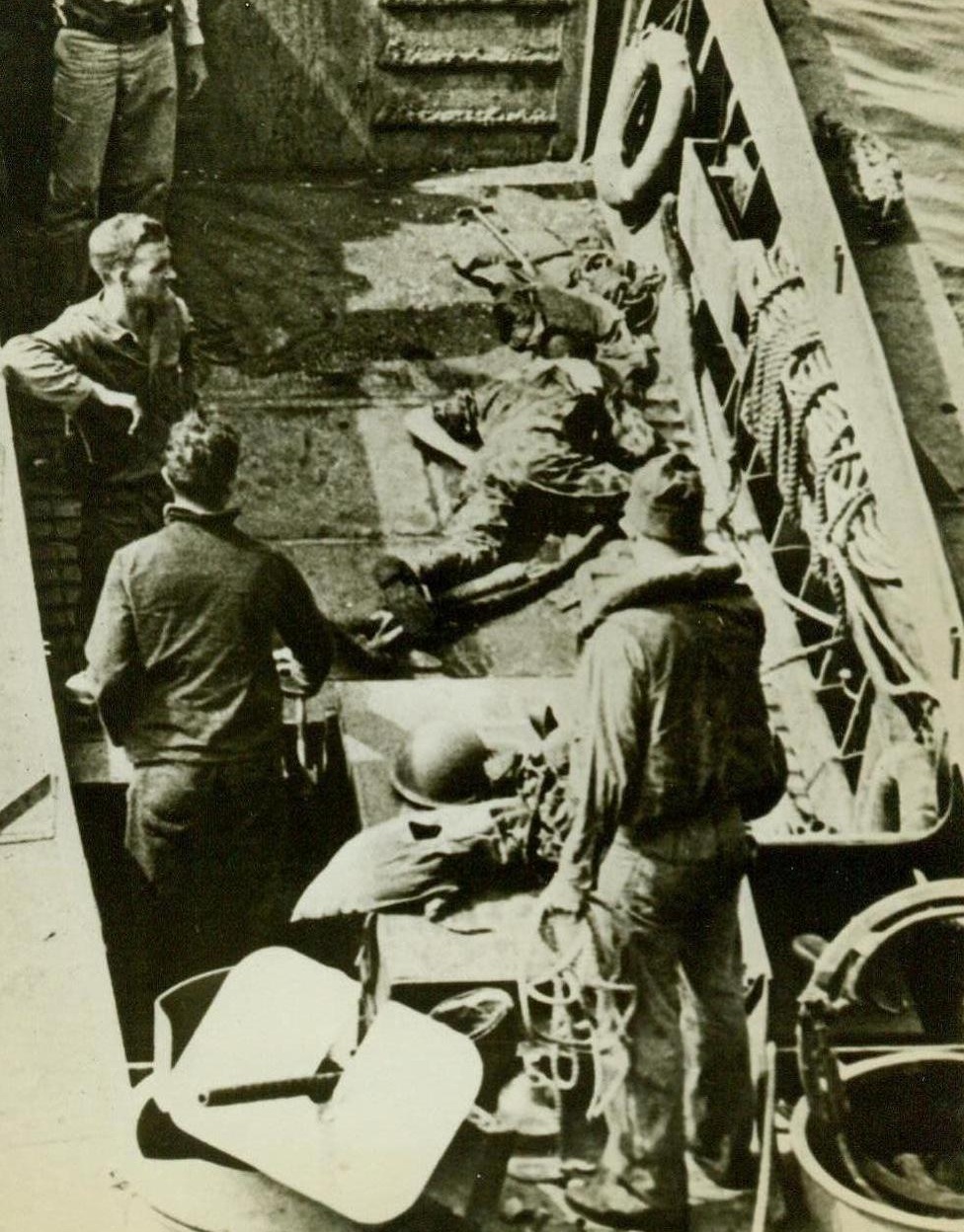 Landing Casualty, 11/15/1943. Bougainville -- A U.S. Marine lies crumpled in the bottom of a landing barge, which is on its way back to the transport after landing troops on Bougainville Island -- One of the toughest landings in the Solomons campaign. The wounded man was hit when the first Marines hit the beach. 11/15/43 (ACME);