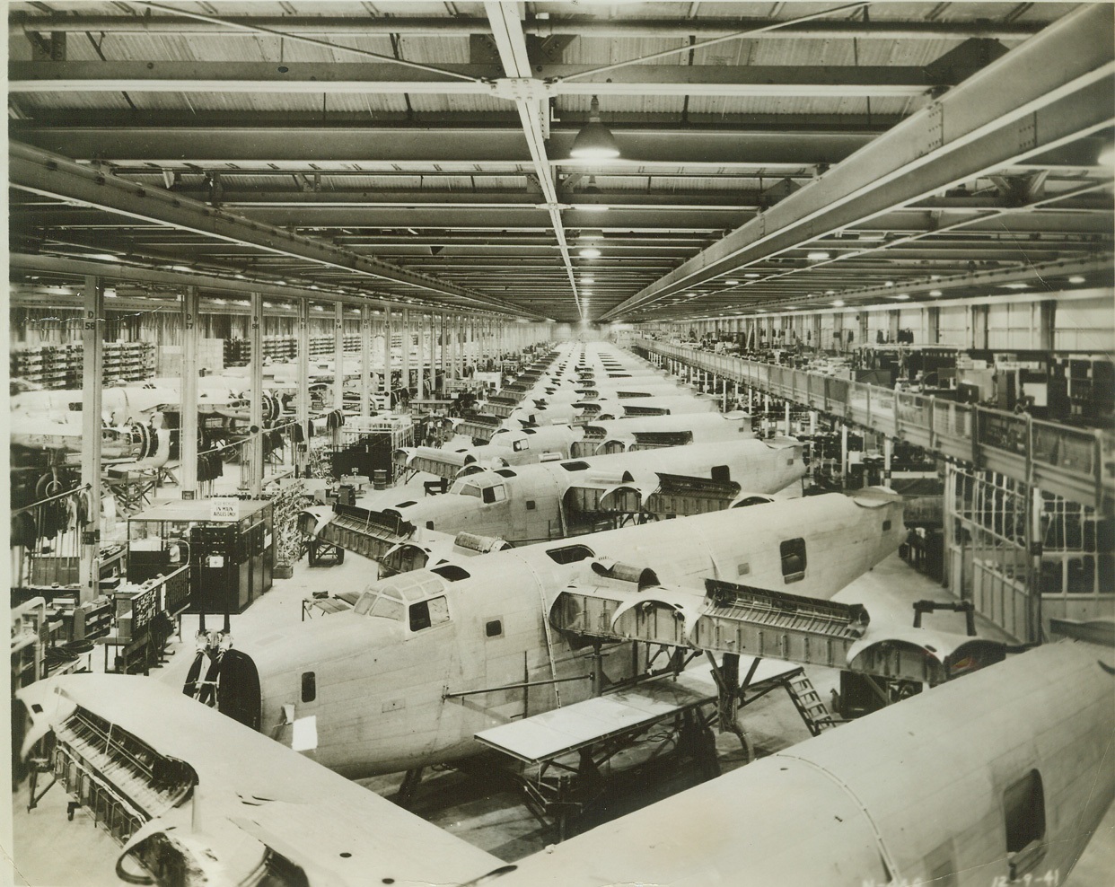 Giant Bombers in Assembly-Line Production, 3/15/1942. SAN DIEGO, CALIF. -- Giant four-motored bombers on a moving assembly line are the Consolidated Aircraft Corporation's answer to the wartime demand for "more planes faster." Almost as far as the eye can reach the line moves along until fully completed planes roll off ready to do battle.  Credit: (ACME);