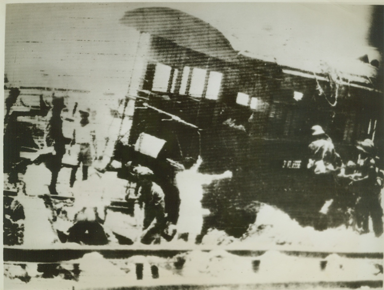 TOMB FOR FIFTY IN SOERABAJA, 3/14/1942. SOERABAJA, JAVA – Rescue workers work to save people trapped when a railroad car under which they had taken refuge during the Japanese bombing of the city was struck by an aerial explosive. Fifty men and women met death under the car. Radioed to New York. Credit: ACME;