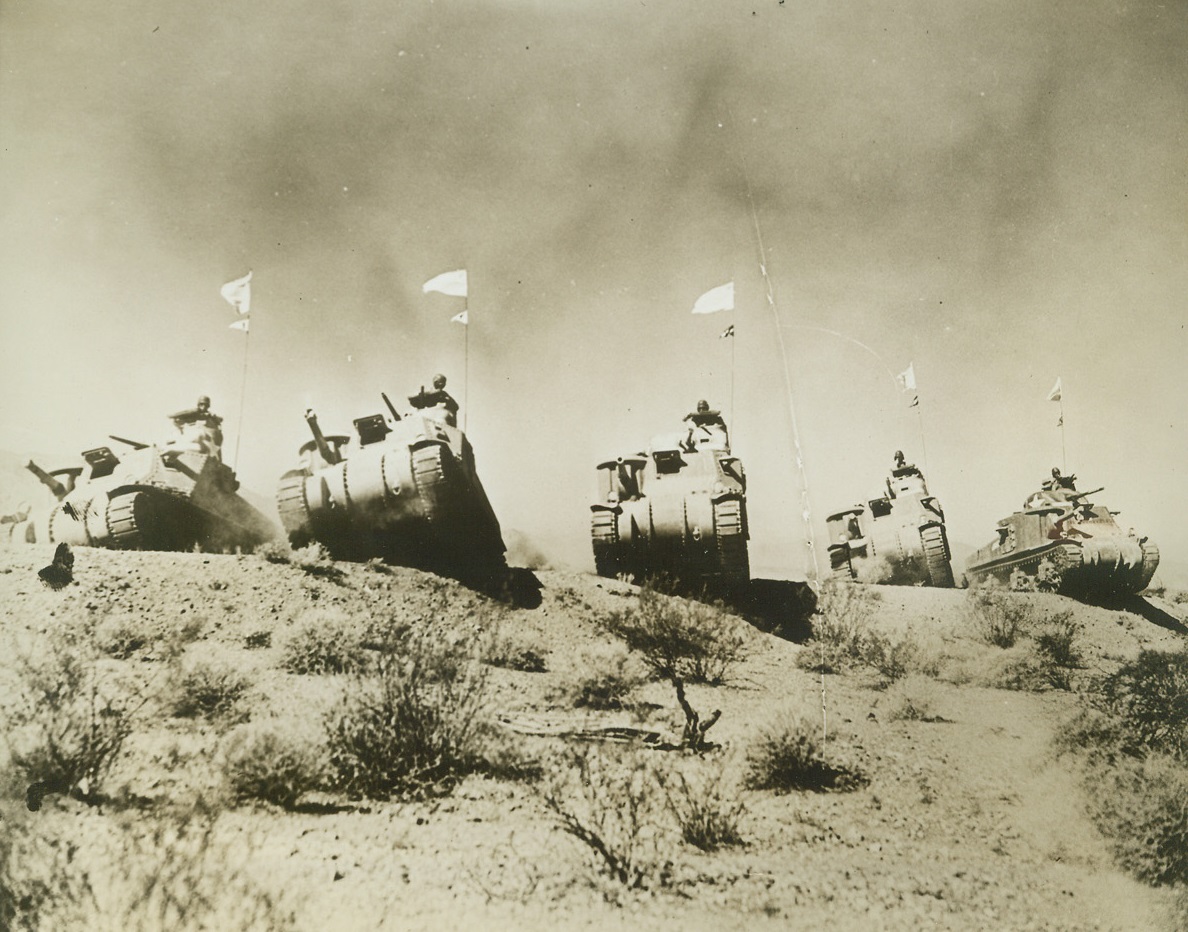 Tank Crews Train for Desert Warfare, 8/27/1942. With U.S. Army in California Desert – Kicking up sand in clouds that darken the sky, these U.S. Tanks clank over a sand dune somewhere in the California desert during extensive battle maneuvers over the world’s most grueling terrain. Credit: ACME;