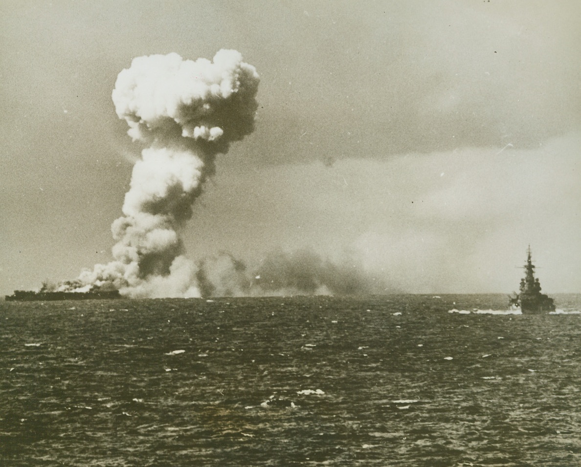 Princeton’s Death Scene, 11/17/1944. Smoke mushrooms from U.S. light carrier Princeton as the doomed ship is torn by explosions following direct hit by Jap bombers in second battle of the Philippine sea.  U.S. warship at right stands by.Credit (U.S. Navy photo from ACME);