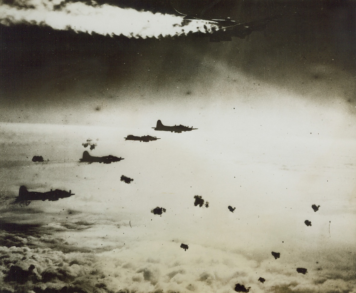 Fortress in Peril, 4/5/1944. BERLIN – Smoke pouring from the flames in one of its engines, a Flying Fortress continues in formation over Berlin during the U.S. 8th Air Force raid on the Nazi city on March 22nd. Intense flak met our warbirds over the target area, but there was no fighter opposition at all.Credit Line (Acme);