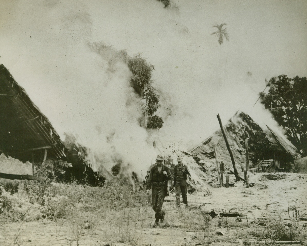 Fire Doesn’t Stop ‘Em, 4/9/1944. Sauder, New Guinea – Men of the 32nd division trudge determinedly on past burning huts in a native village in the Saidor, New Guinea, area.  The homes were set aflame by mortar, grenade and rifle crossfire between allied and Jap troops.  Yanks and Australians continue to give the Eastern end of the axis plenty to worry about in the Northern portion of New Guinea towards Madang.  Credit line (official Signal Corps photo from ACME);