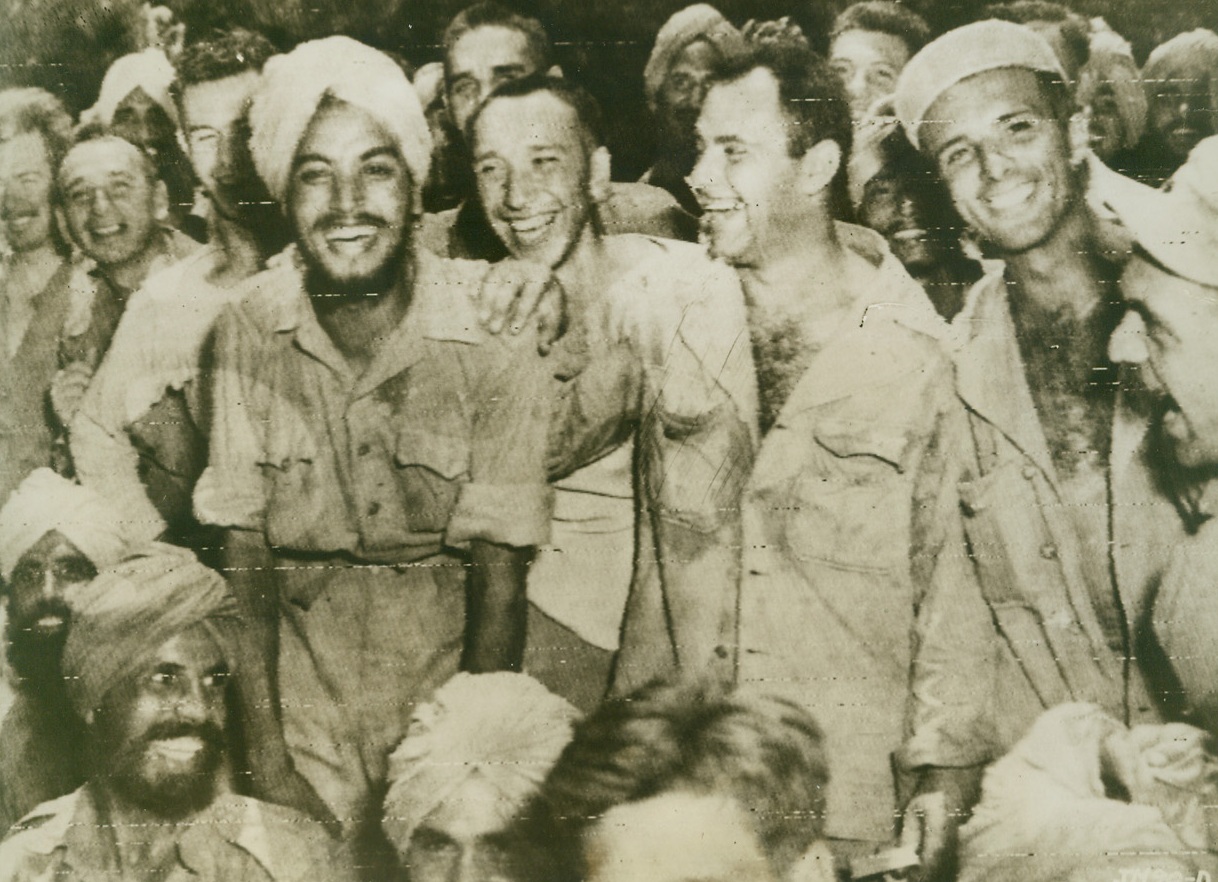 HAPPY DAY, 5/13/1944. NEW GUINEA—Turbaned Indians of the “Sikh” troops grin joyously as they get acquainted with Yanks at a base in New Guinea. The Indian soldiers, captured at Singapore and formed into labor battalions by the Japs in the Admiralties, were liberated by Gen. MacArthur’s invading forces. The remarkable success of the Allied invaders has made it a happy day for Sikhs and Yanks alike, and their broad grins bear this out.  Credit (US Army Radiotelephoto from ACME);