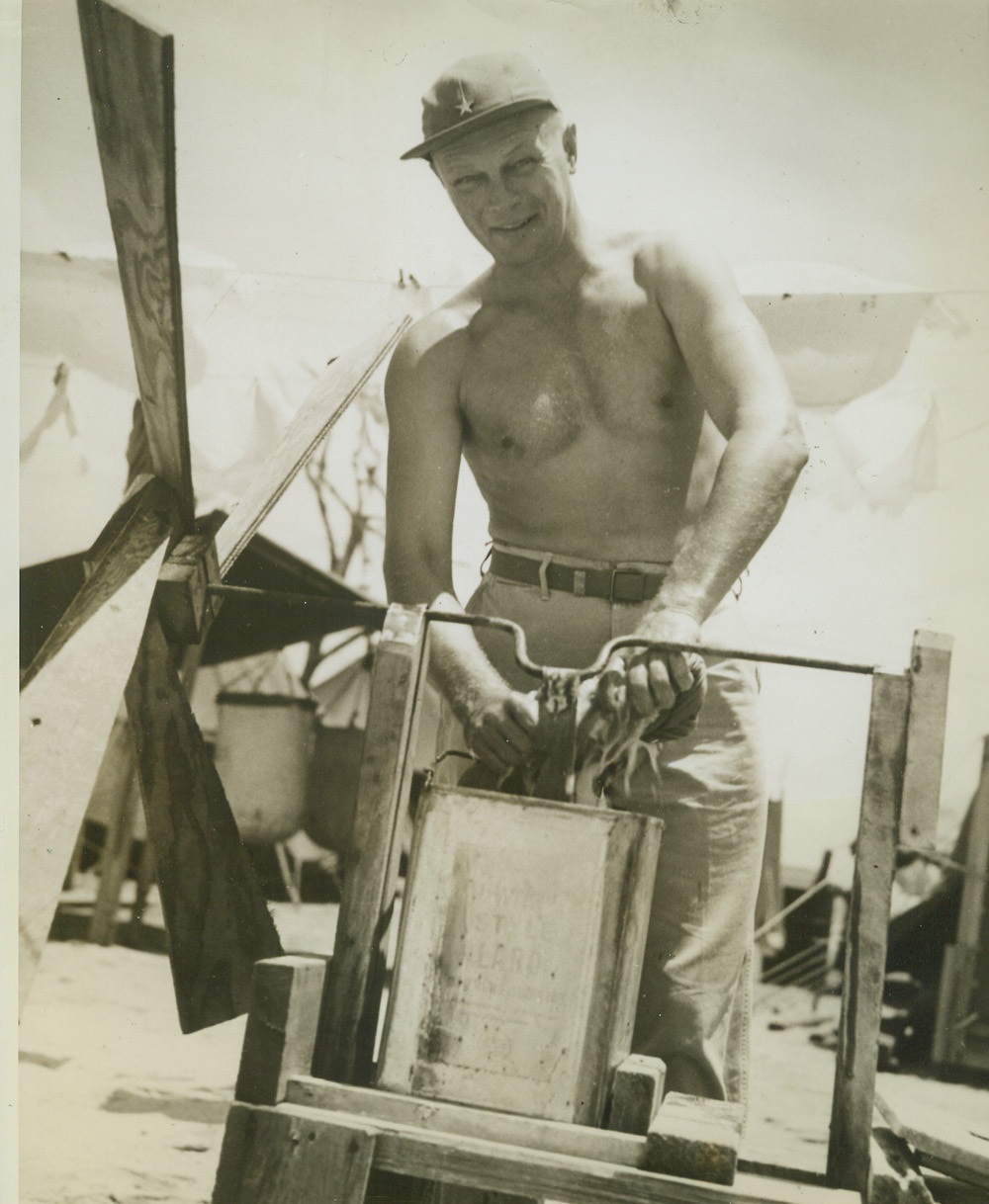 Everybody Does It In the Army, 5/10/1944. SOUTH PACIFIC -- Brig. Gen. T.H. Landon of Los Angeles, Calif., commander of the 7th Army Air Forces Bomber Command, does his washing in a home-made windmill washing machine at an advanced base somewhere in the South Pacific. Seems that the Army has its help problem as well as civilians. Credit:-WP-(ACME);