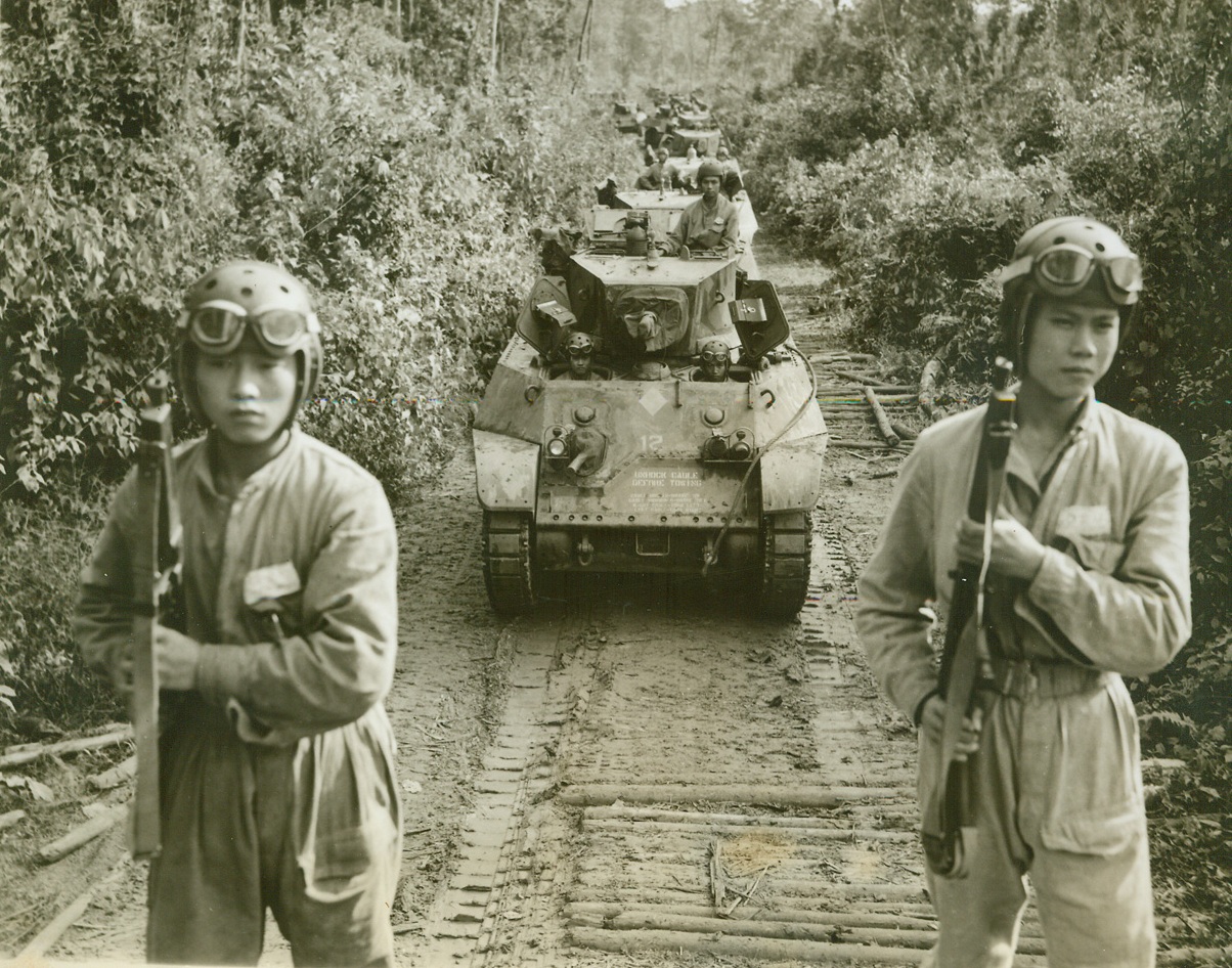Yank Tanks Make Debut in Burma, 5/20/1944. Burma – To the American and Chinese jungle fighter troops in Burma have been added new mechanized units-American tanks. Now being used in the Hukawng Valley, the tanks have played a prominent part in driving back the Jap forces with resultant Allied gains. The Chinese soldiers who man the battle wagons have been trained by Americans and are fully equipped to use their vehicles to the best advantage. The tanks reached the battle area in Hukawng Valley by traveling over the newly constructed Ledo road, from Assam to the Valley. The following pictures show the tanks in use in their new territory. Flanked by an advance armed guard the tanks move down a small road hacked out of the jungle in the combat zone in Burma. Note the logs stretched across the road – they aid the tanks in traversing the gooey mud which is so characteristic of the Burma Jungle. Credit: ACME photo by Frank Cancellare, War Pool Correspondent;