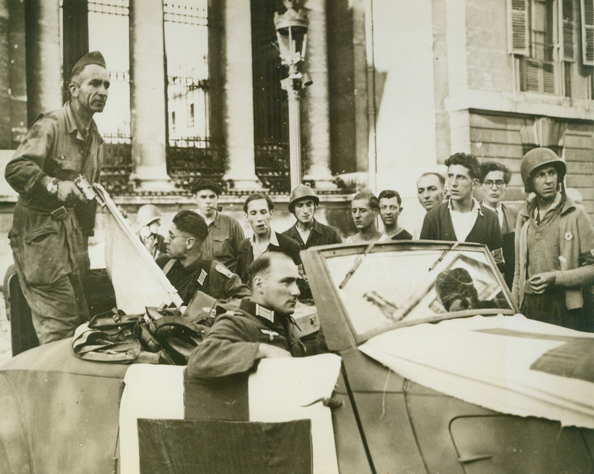 NAZIS SURRENDER CHAMBER OF DEPUTIES IN PARIS, 8/30/1944. FRANCE—Two Nazi officers who were part of the 400 Germans who barricaded themselves in the Chamber of Deputies in Paris and fought off liberating troops, wait to be driven away after their surrender to French partisan forces. The flag of truce is in the back of the car.Credit: Acme;