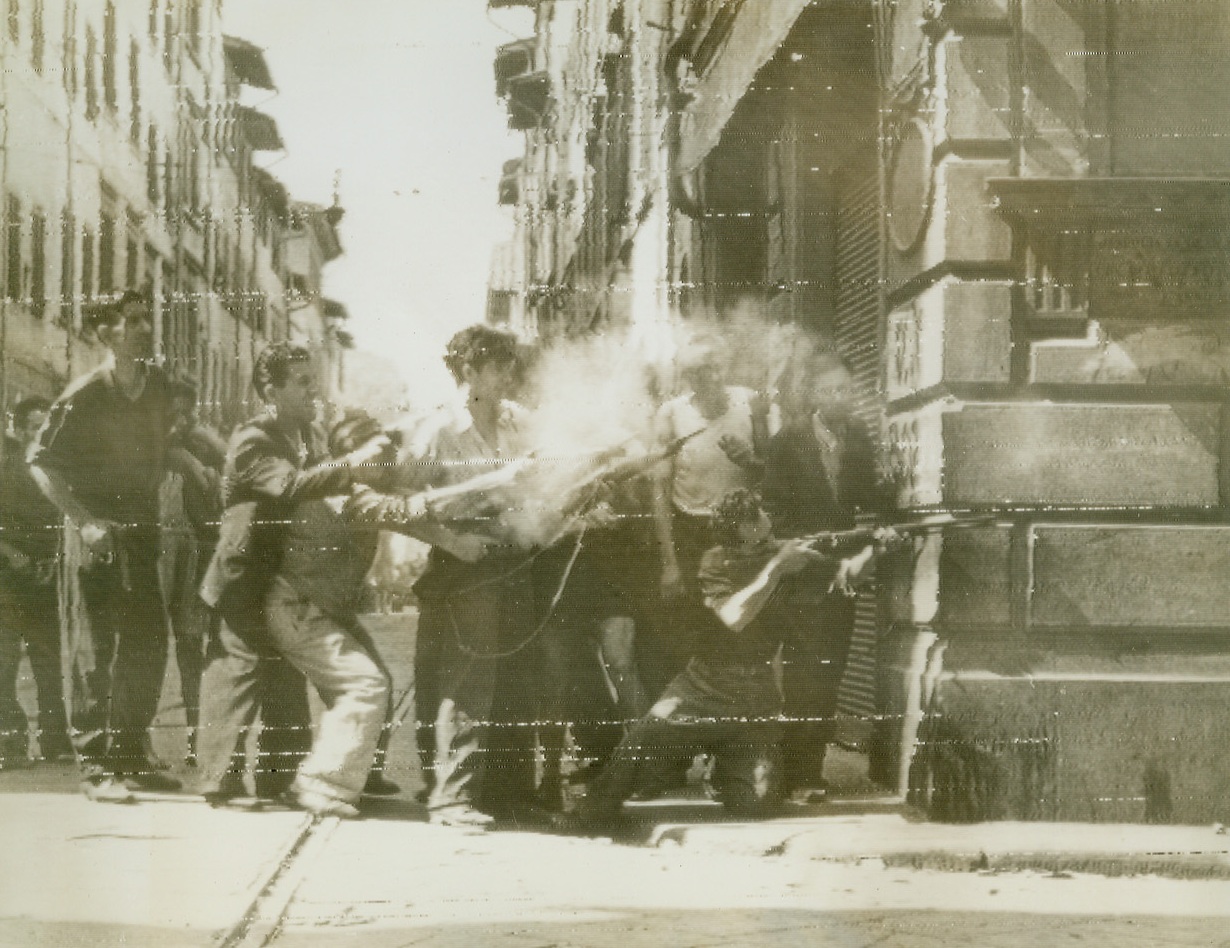 Street Fighting in Florence, 8/8/1944. FLORENCE, ITALY – As units of the South African troops of the British 8th Army enter the outskirts of Florence, hub of the Germans last defense line in Italy, anti-fascists lean out from the shelter of a building and fire around a street corner at German forces within the city. These civilians have given great aid in stemming the fighting of German and Fascist snipers.Credit (British Official Radiophoto via OWI from Acme);