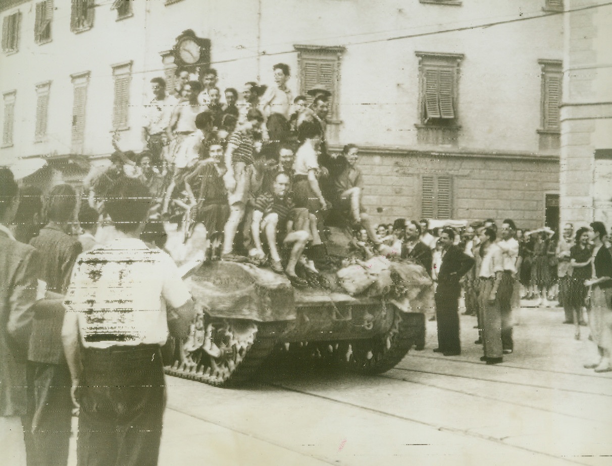 Florentines Welcome British Army, 8/8/1944. FLORENCE, ITALY – Jubilant youngsters jump atop a British tank as the people of Florence fill the streets to welcome a unit of the British 8th Army entering the city’s outskirts. Clock in the background reads 9:25. Credit (British Official Radiophoto via OWI from Acme);
