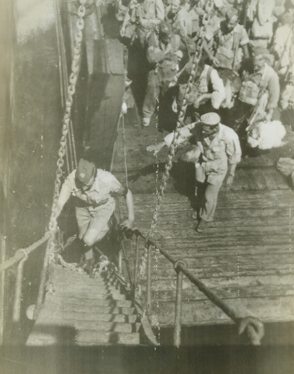 On Their Way to France, 8/15/1944. ITALY – Walking up the gang-plank as his comrades wait their turn on the dock below, a ground crew member of the Royal Air Force boards a vessel at an Italian port headed for the new invasion front in southern France.Credit (OWI Radiophoto from Acme);