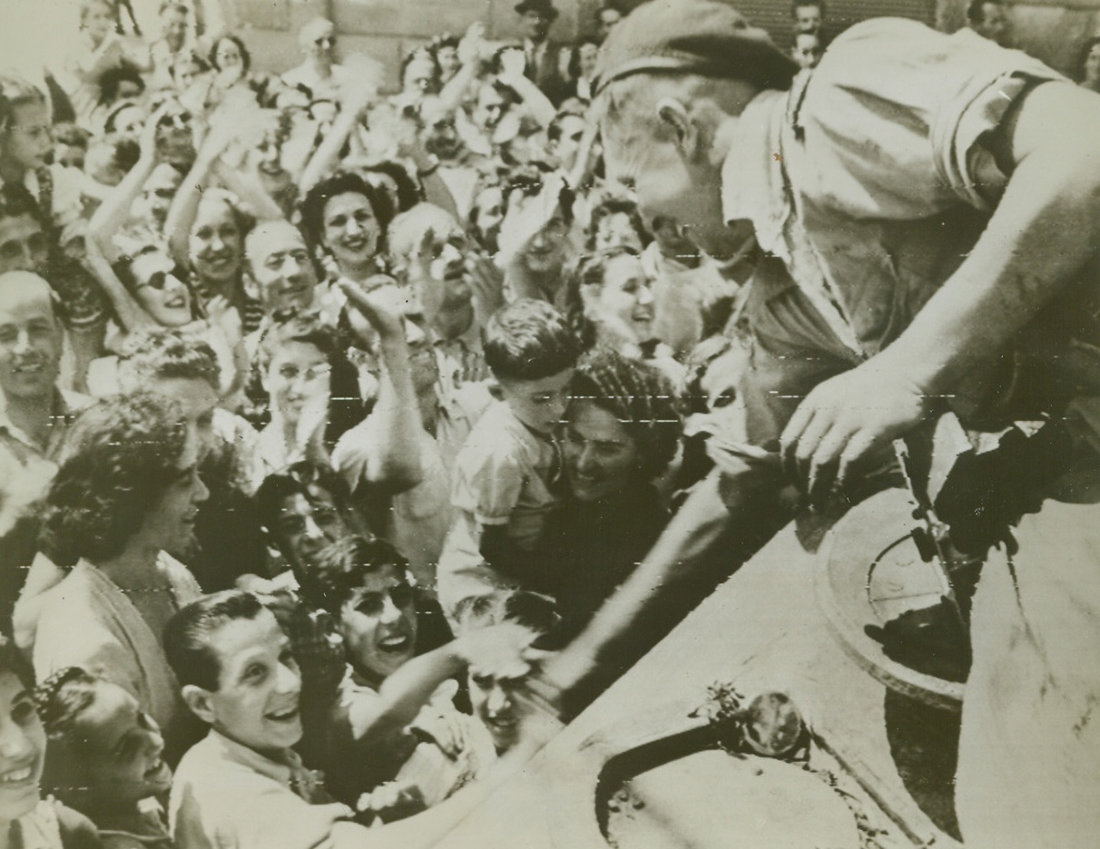 Welcome to Florence, 8/7/1944. FLORENCE, ITALY – Waving and smiling their greetings to the Allied Liberators, joyous Florentines welcome victorious troops at the southern outskirts of their city. A member of a South African tank crew leans down to shake friendly hands.Credit (Signal Corps Radiotelephoto from Acme);