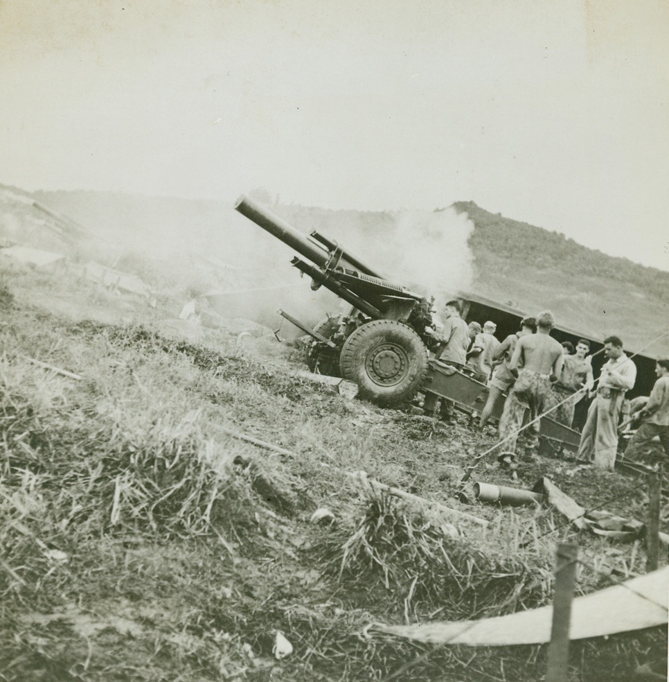 BLAST JAPS OFF GUAM, 8/11/1944. GUAM—A Marine howitzer, one of the first to be brought ashore, blasts enemy positions in the battle for Guam, the first American base to be taken by the Japs and the first to be recovered from them. More than 10,000 Japanese were killed in the fighting for the island. Credit: U.S. Navy photo from Acme;