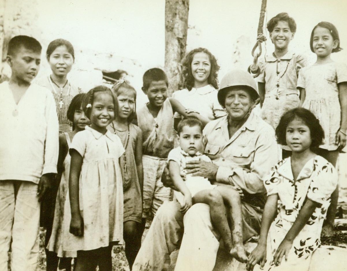 Benevolent General, 8/12/1944. Guam – Smiling Maj. Gen. Roy S. Geiger, USMC, commander of US Expeditionary Forces on Guam, holds one sober-faced native child on his lap, while others surround him, grinning cheerfully. The children were rescued from the Japanese by American forces 8/23/44 Credit (ACME);
