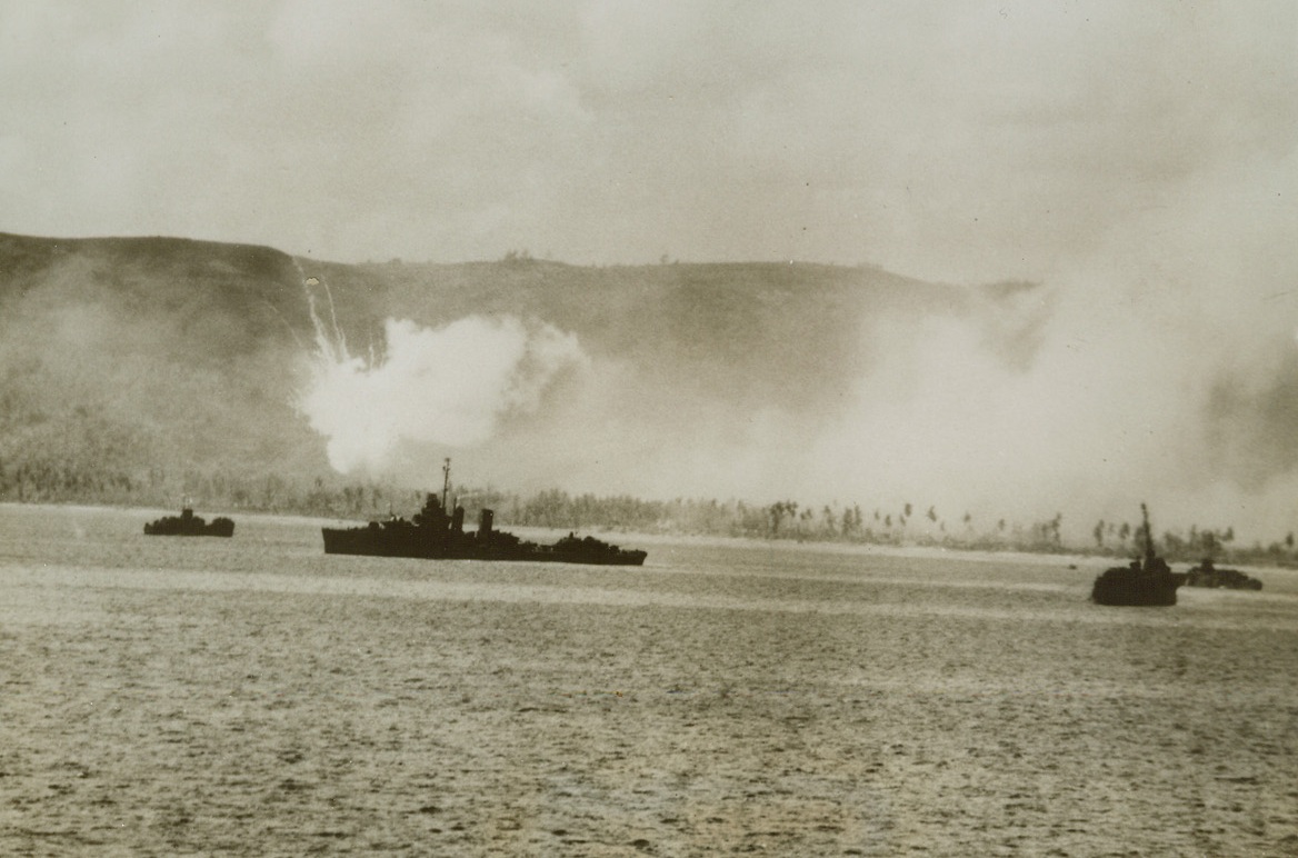 Fire and Brimstone on Guam’s D-Day, 8/2/1944. Guam Is. – A phosphorus shell explodes in a burst of burning fog, and US ships move into the harbor at Guam as landing assaults are launched against the Japanese stronghold. The landings were preceded by aerial and surface bombardment.Credit: US Navy photo from ACME;