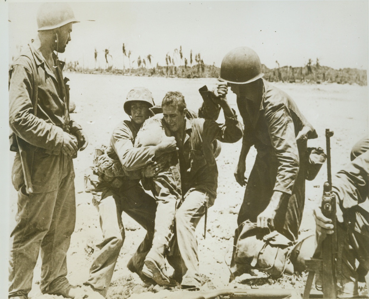 His Buddies to the Rescue, 8/6/1944. GUAM -- A Leatherneck swings a fellow Marine, who was hit by a Jap bullet in fierce fighting for an airstrip near Orote, to his shoulder and other Marines clear the way for him as they carry the wounded man back to an emergency station. Credit (ACME) (WP);