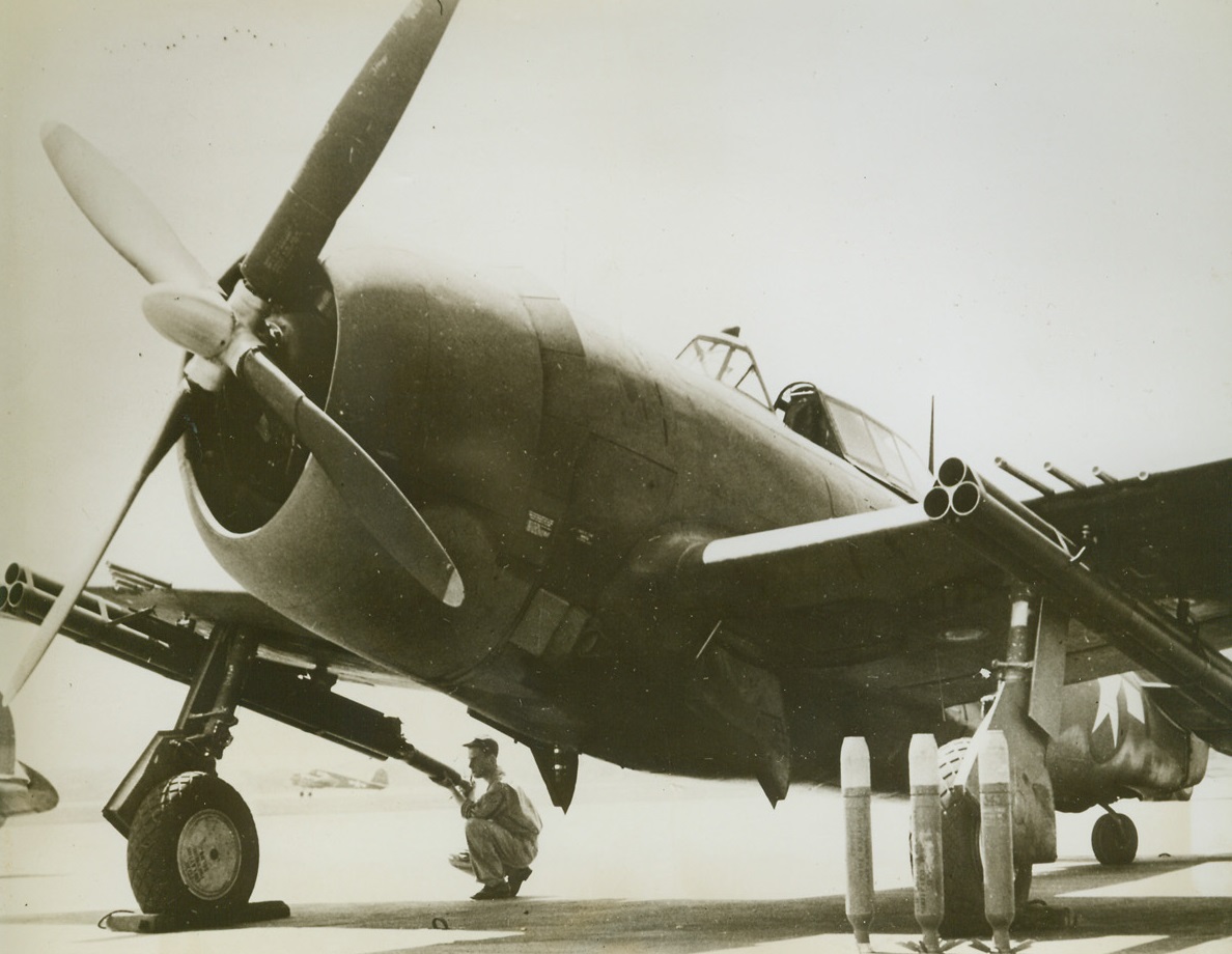 Thunderbolt Bristles with Guns, 8/1/1944. A soldier loads a projectile into the rocket armament of the far wing of a P-47 Thunderbolt. This plane is a deadly weapon of war with its eight .50 caliber machine guns and new rocket armament. Here is a closeup of the plane with its machine guns and the rocket gun armament under both wings. Three of the rockets are standing on end before a wheel of the plane. Credit: USAAF photo from ACME;