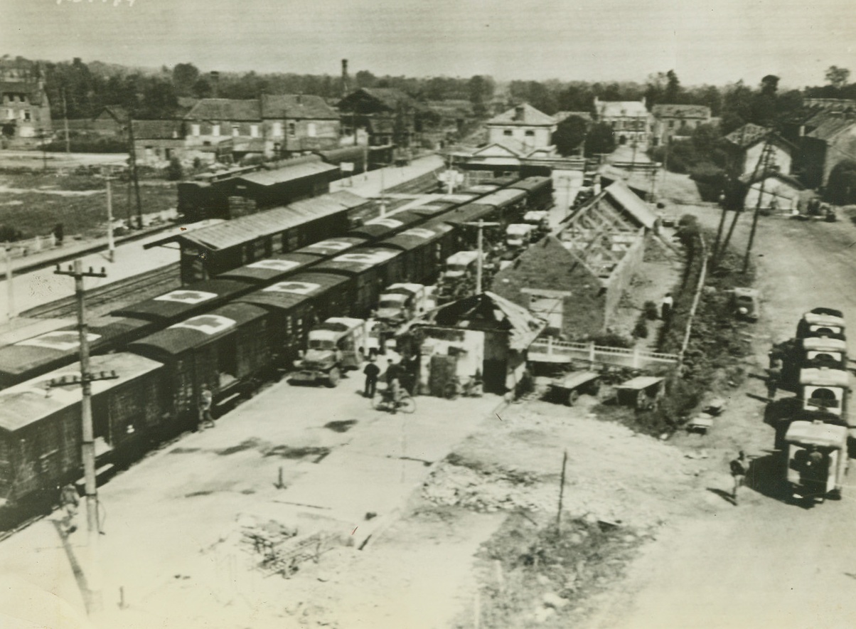 LOADING FIRST HOSPITAL TRAIN, 8/8/1944. FRANCE – The first allied hospital train to operate in France since D-day, is loaded with wounded from ambulances, at Lison.  The train is made up of boxcars left by fleeing Germans. Wounded are taken to Cherbourg on their way to England.  Credit: Army radio telephoto from Acme;