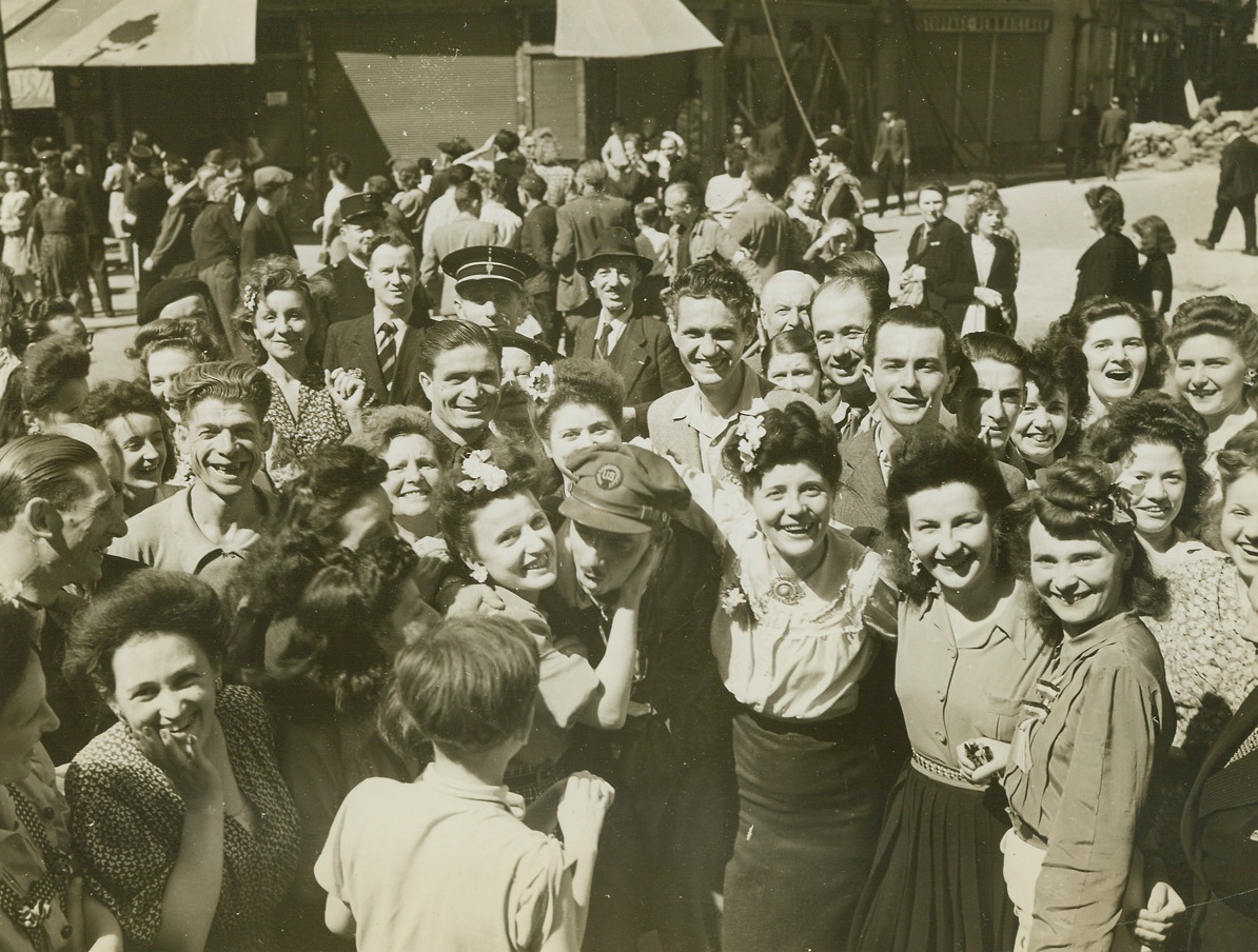 ACME Photog Gets Hugs And Kisses, 8/30/1944. France – Wildly enthusiastic French girls greet ACME Newspictures Photographer Bert Brandt with hugs and kisses as he entered Paris with the first group of liberating forces. Brandt’s pictures of the freeing of the French capital, along with other ACME photographers’ photos, were the first to reach the United States. Credit: ACME photo by Bert Brandt, War Pool Correspondent;