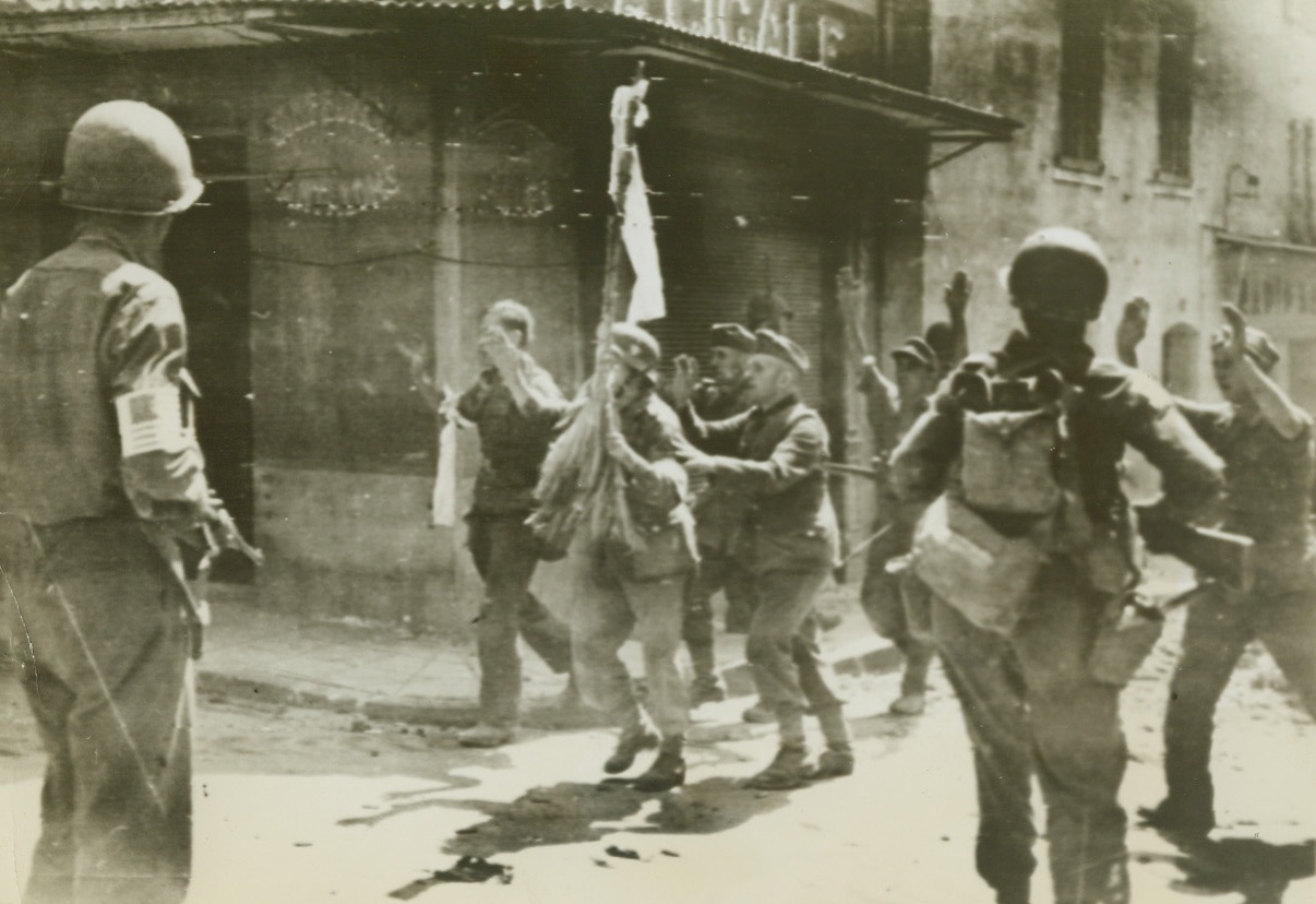 New Nazi’s “Standard”, 8/17/1944. France – While one of their number holds the white flag of surrender aloft, Germans rush out to give themselves up to American troops at a street corner in a little town east of Toulon. Note how two of the Nazis hide themselves behind the flag bearer – as though they expected to feel lead from Yank guns at any moment. (Passed by Censors) Credit: ACME photo by Sherman Montrose for War Picture Pool;