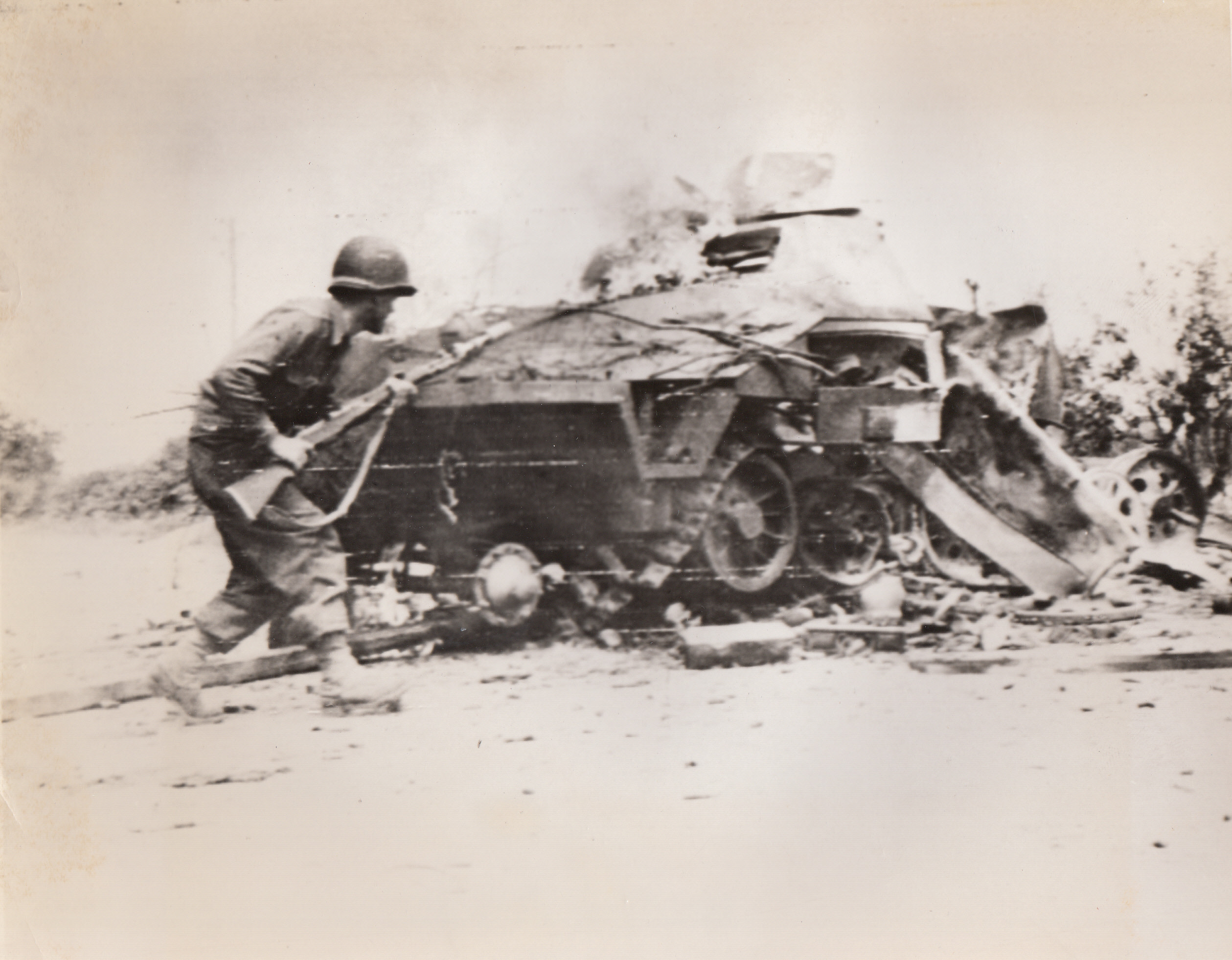Lesson In Caution, 8/14/1944. France – With cautious step, Sgt. Andrew Harding, Bridgeport Conn., approaches a burning Nazi armored car. The vehicle had been knocked out on the road to La Mont by an American three-inch shell.;