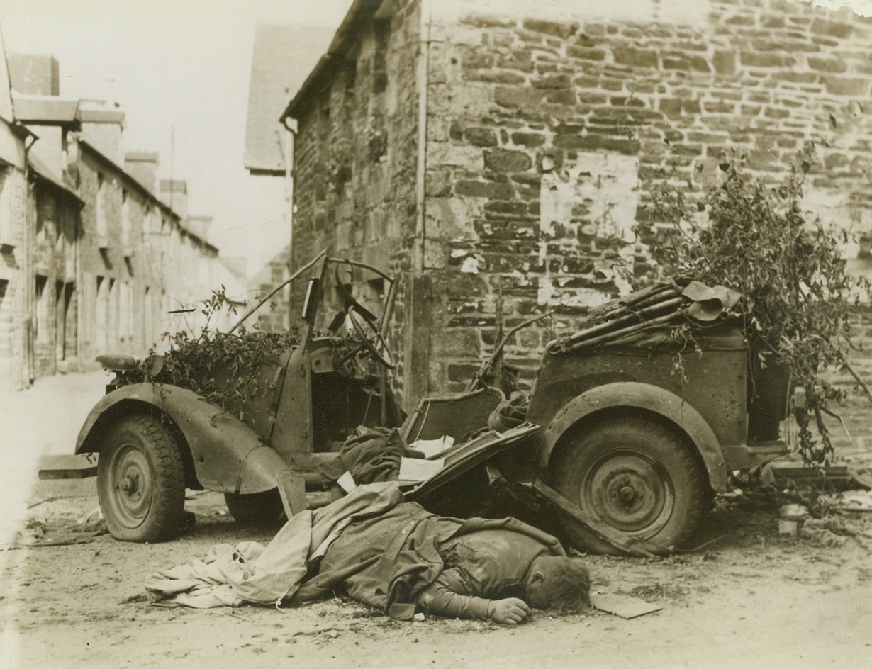 Nazi Reaches End of Journey, 8/15/1944. France – Face down in the dust of a road, a German soldier lies dead beside his Volkswagon in Barenton, France. Marks of blood line his face. American troops took the town in latest drive through France. Credit: Signal Corps photo from ACME;