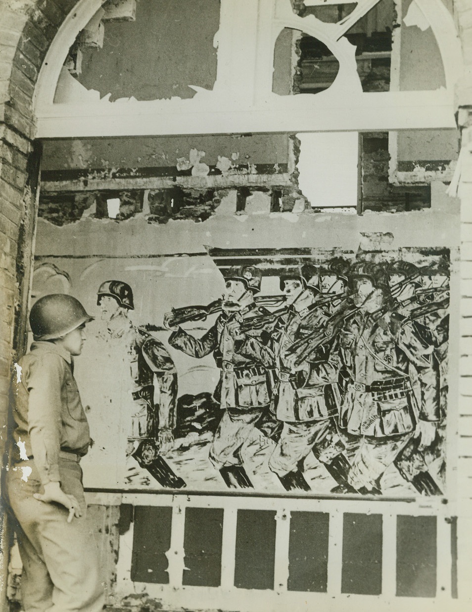 Nazi Victory Painting Premature, 8/4/1944. France – In a captured German headquarters in France an American soldier examines with interest an unfinished painting of German troops marching in victory. Nazis did not have time to complete it before evacuating before the relentless drive of the Allies. Shell fire has knocked holes in the mural. Credit: ACME;