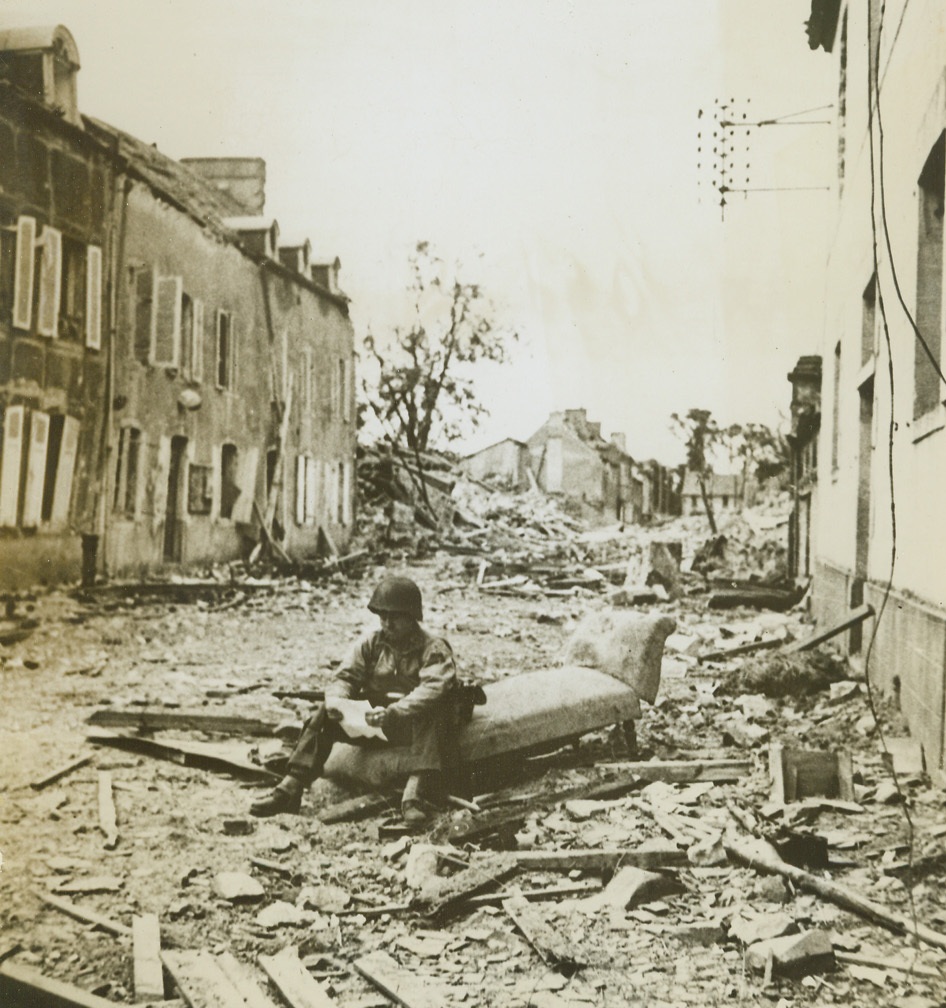 A Bit of Home in France, 8/9/1944. France – Amid the destruction and ruin of St. Sauveur Lendelin, Cpl. Floyd Davis, Nashville, Tenn., sits on an old settee and reads a letter from home. A bit of home injected into this scene of warfare makes for contrast and relief from thoughts of death, destruction, and disaster. Credit: ACME;