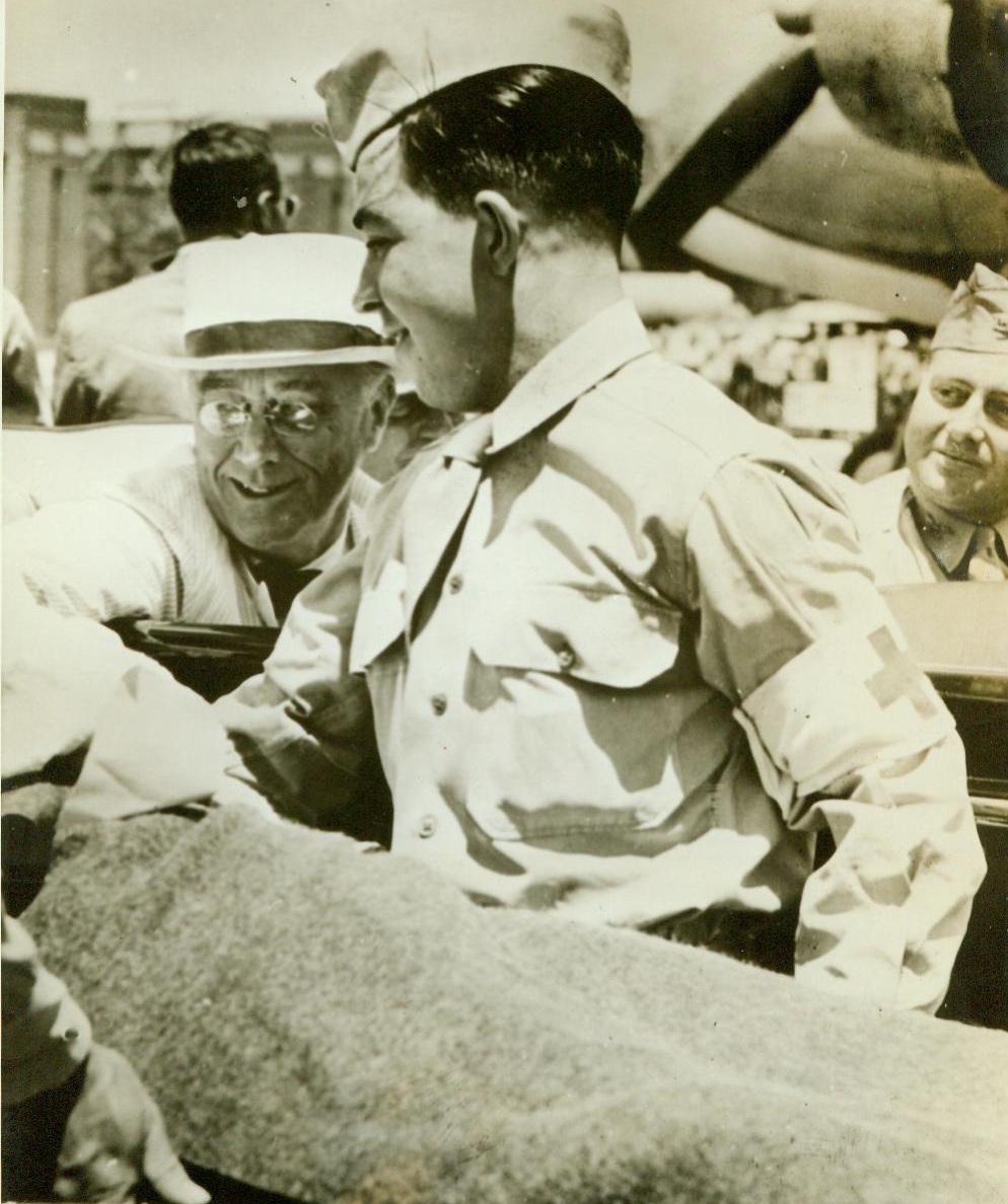 President Chats With Saipan Casualty, 8/10/1944. Hawii-- President Roosevelt (Left Background) chats with a wounded soldier (On Stretcher) at an airfield in Hawaii, during the Chief Executive's recent visit there. The wounded man, whose face has been deleted by censors, has just been flown in from Saipan. 8/10/44 (ACME);