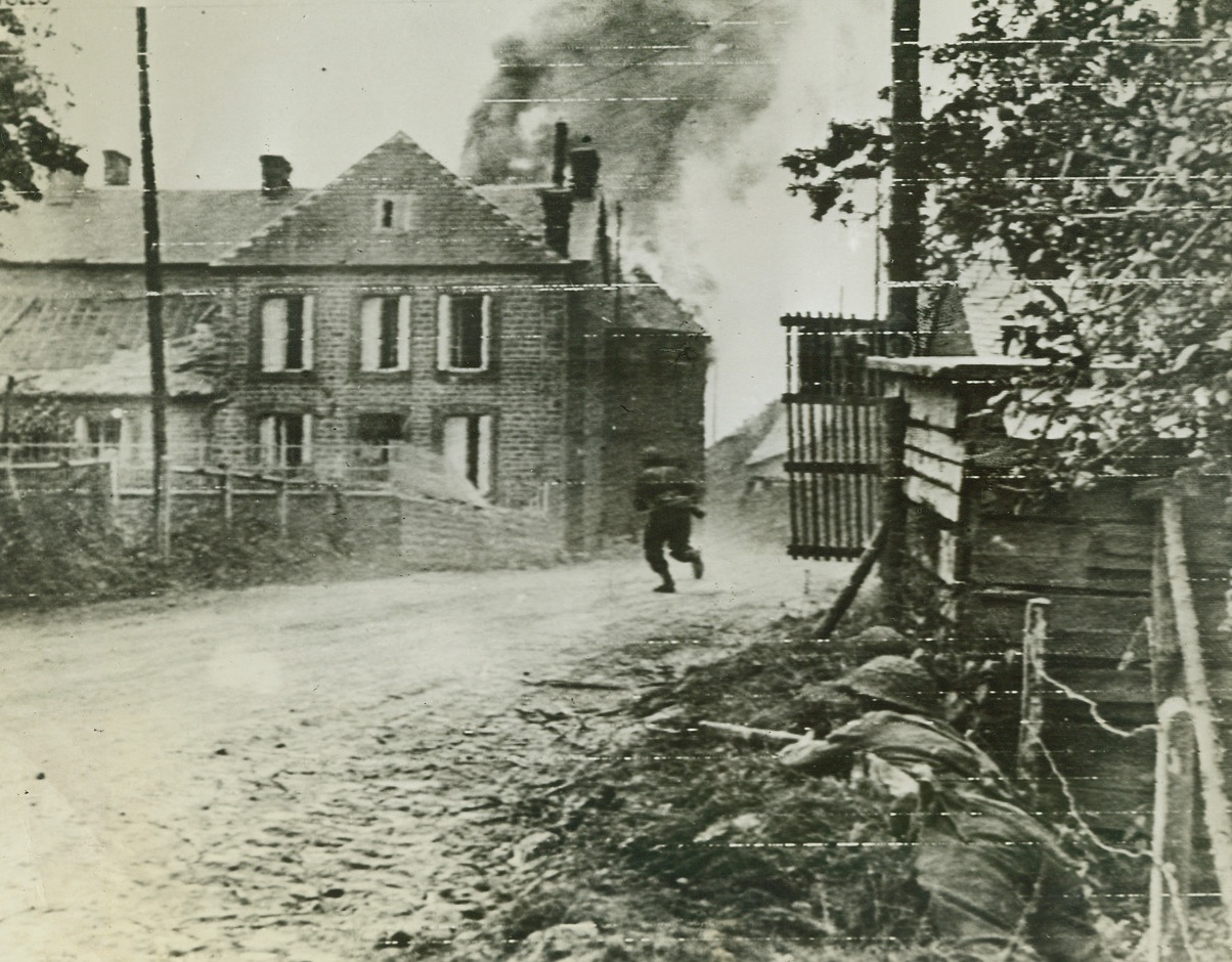 Looking for Snipers, 8/8/1944. France – A British infantryman, his gun held ready, dashes across a road in Montchauvet, while two of his buddies (right, foreground) cover him. The men are after snipers hiding in buildings in background. Credit: British War Office photo via Army Radiotelephoto from ACME;