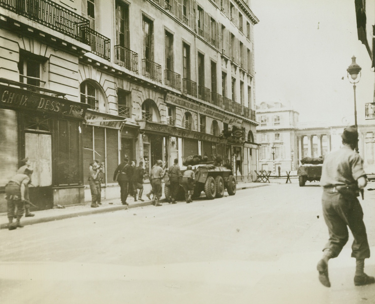 France Regains Its Chamber of Deputies, 8/30/1944. France – American and French troops deploy cautiously, taking what cover they can find behind armored vehicles, to attack a German garrison of some 400 men barricaded in the famous Chamber of Deputies in Paris. The Chamber is at the foot of this street. Credit: ACME;