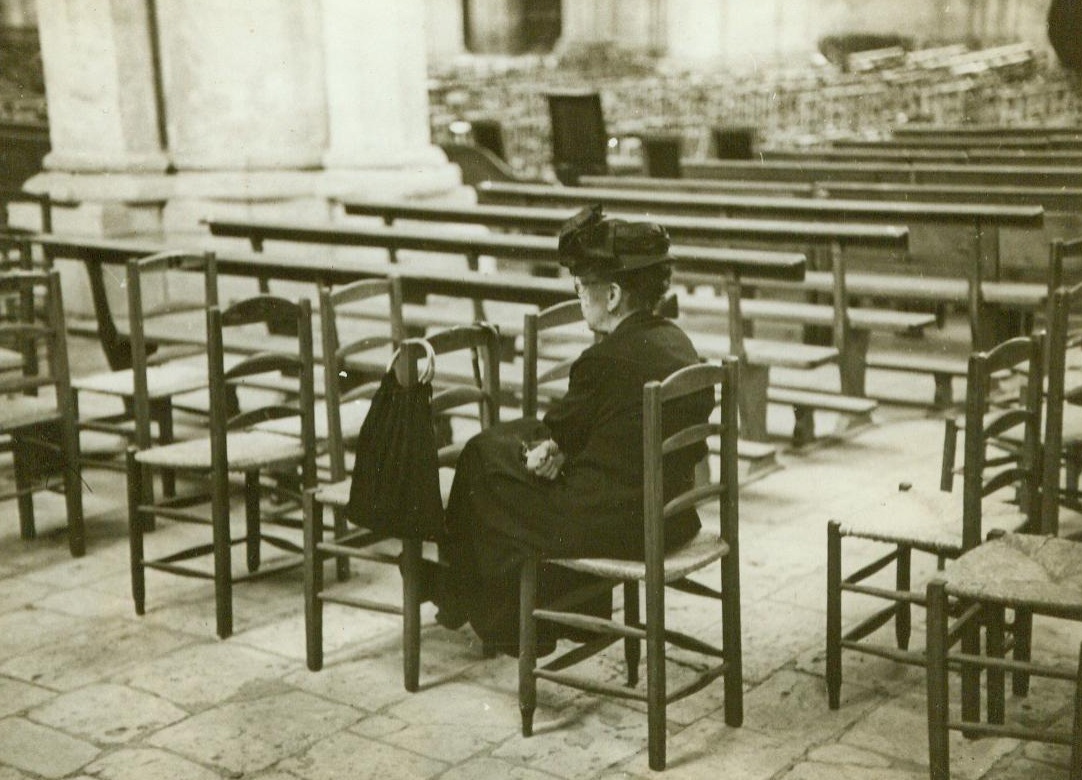 Giving Thanks In Her Way, 8/26/1944. Chartres, France -- While the streets outside are filled with crowds wildly cheering the liberation of Chartres by Yank Forces, this lone French woman sits quietly in the Cathedral giving thanks in her own way. Later the Cathedral  will be filled as the townspeople gather for Thanksgiving services. 8/26/44 (ACME);