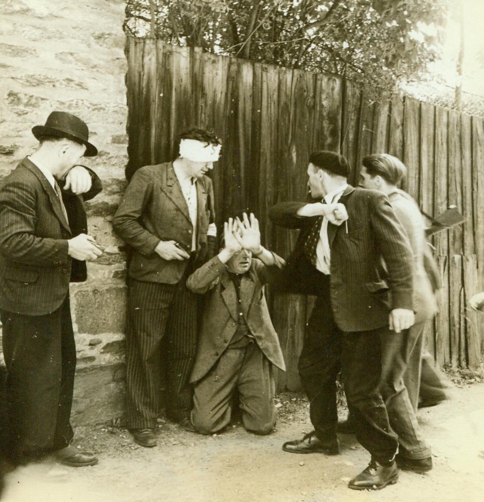 Cringing Before His Judges, 8/12/1944. Rennes, France -- The day of judgment has arrived for this collaborator in Rennes, as he cringes on his knees before the wrath of French citizens. One man (with head bandage) holds a small revolver, while others take swiping blows at the traitor. The frightened man, who cooperated with the Nazis during their occupation of the city, was made to say "Vive De Gaulle" and "Viva La France" over and over again. 8/12/44 (ACME);