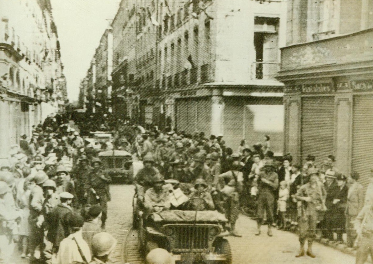 Cheering Patriots Line The Road, 8/6/1944. Rennes, France -- Natives of rennes, both young and old, line the sides of this street in the liberated city, raising their voices to cheer the victorious Yanks. Our warriors returned the cheers as they marched or rode through the heart of the Breton capital. 8/6/44 (ACME);